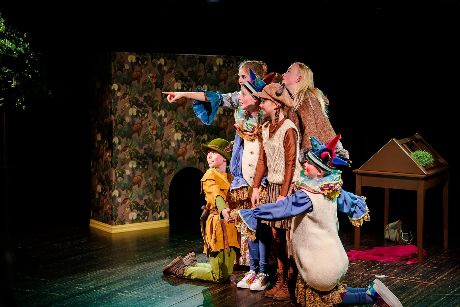 Jente som står og peker med hånden, og flere tilskuere rundt henne som kikker i retningen hun peker