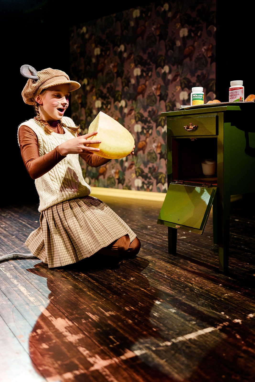 Jente utkledd som en mus, som tar en gigantisk ost ut av et gammelt skap