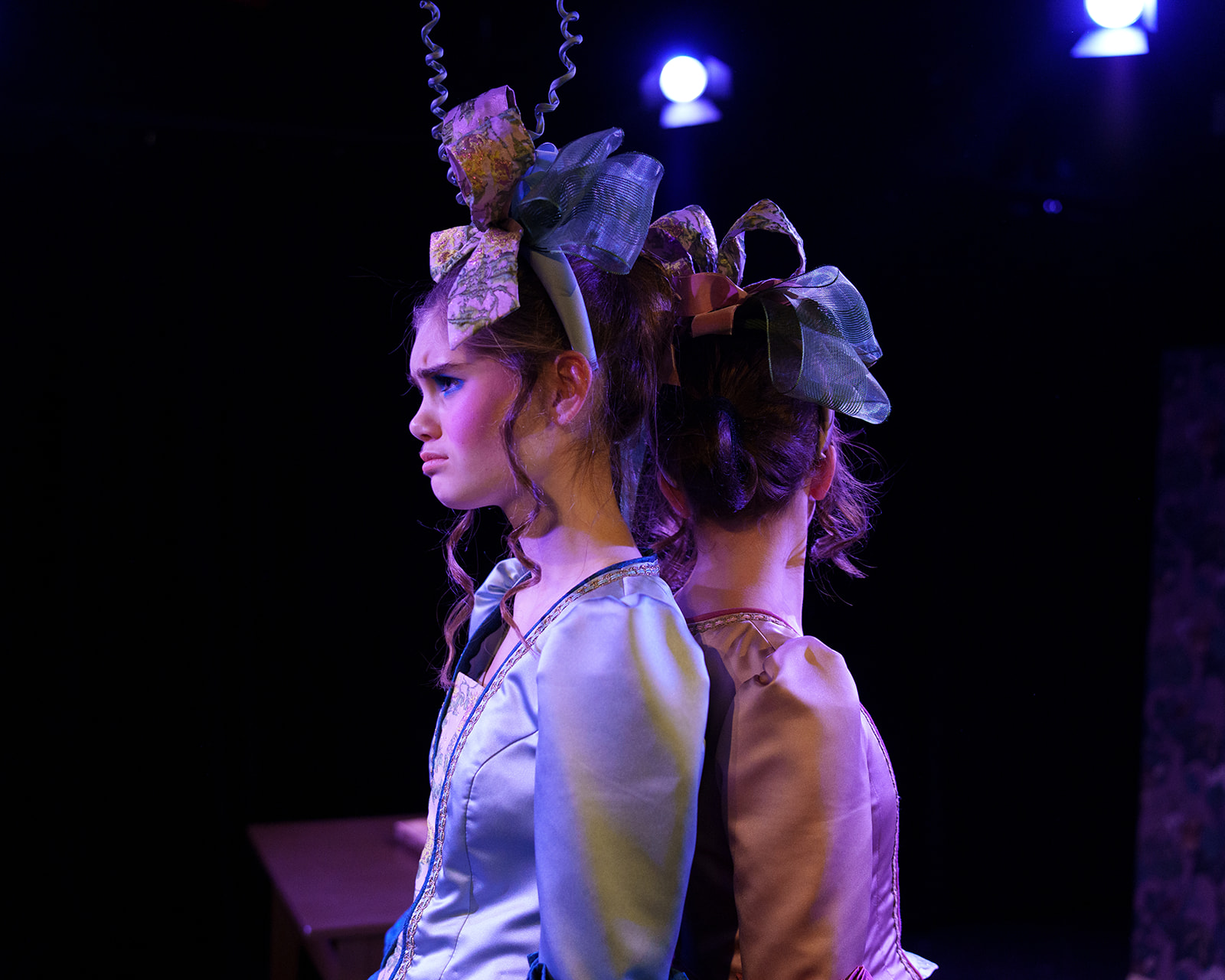 To prinsesser som står rygg til rydd i et mørkt rom