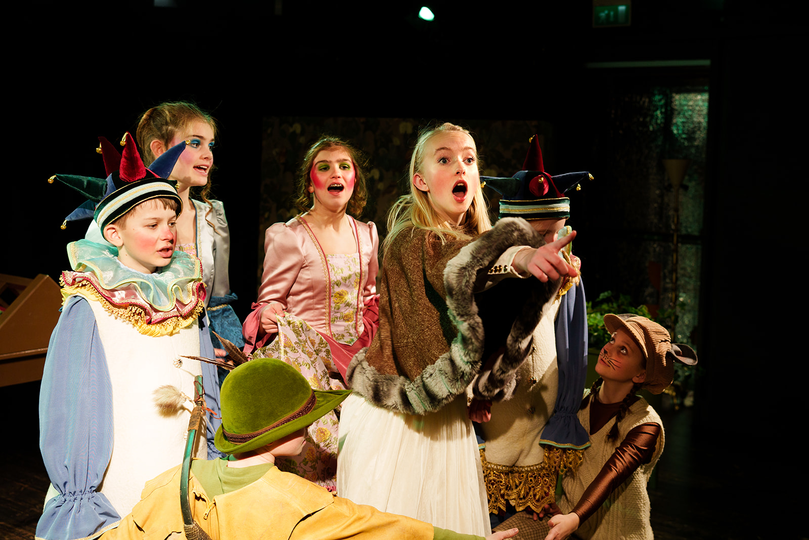 Seks unge skuespillere i flotte kostymer synger.