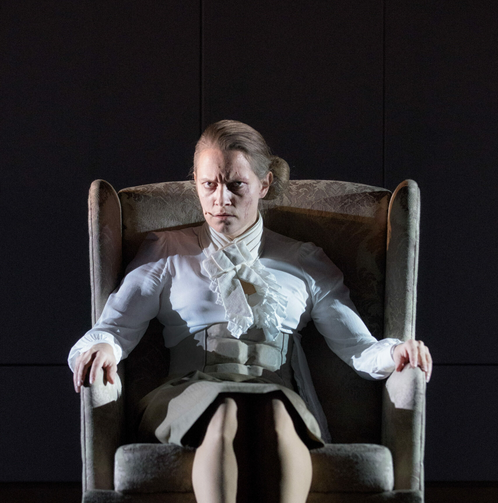 Dame som sitter i en stol med et sint blikk.