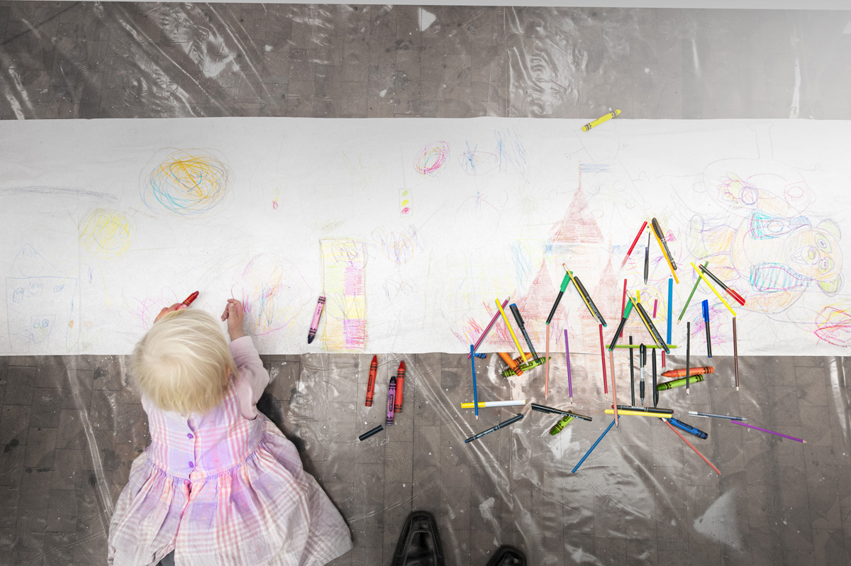 en liten jente som ligger på gulvet og tegner