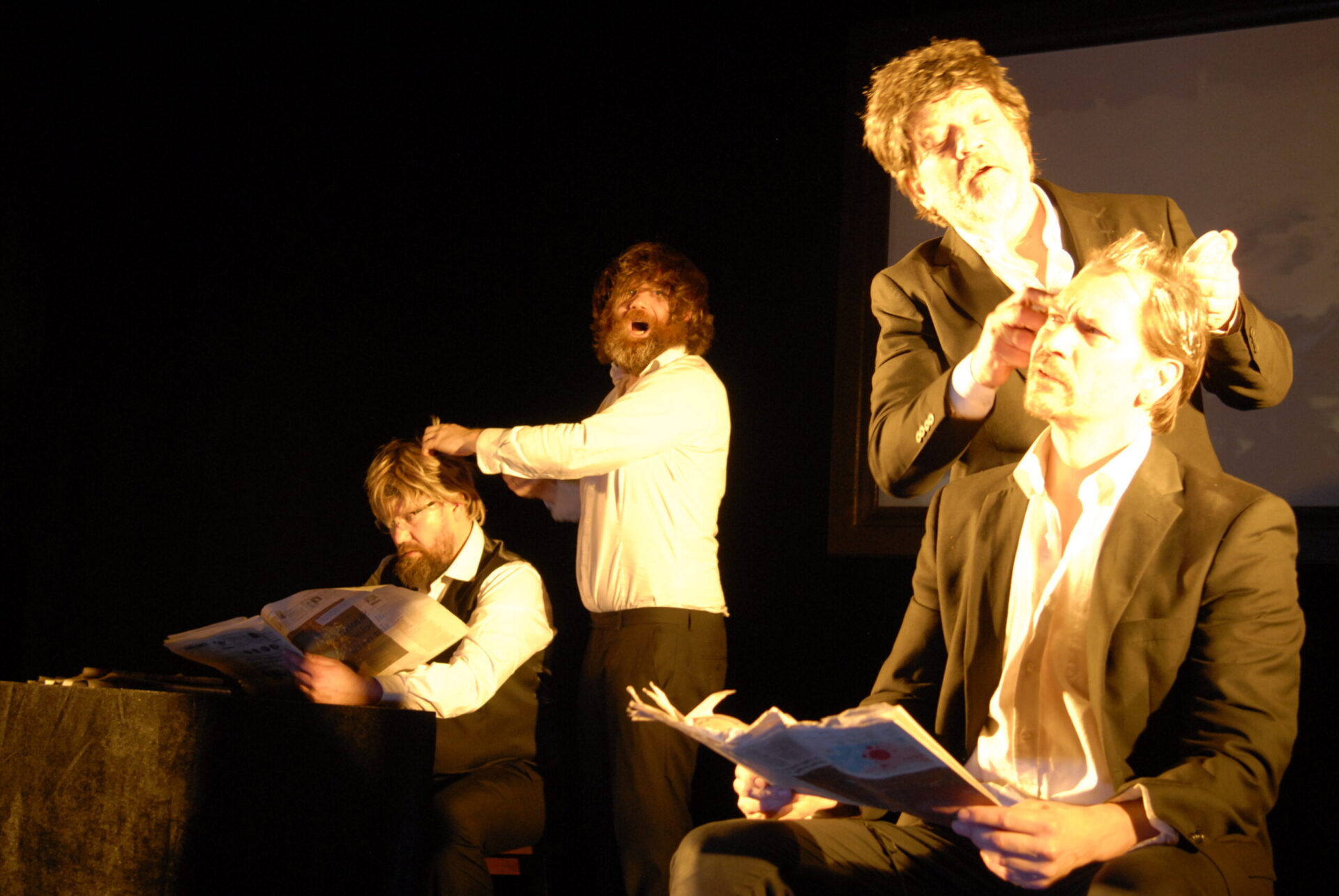 Fire menn i et rom der to holder på med håret til de andre to.