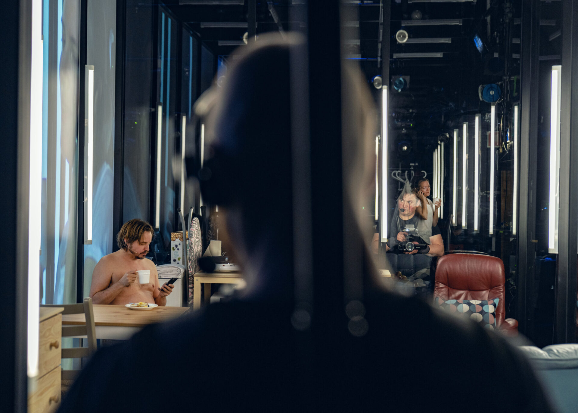 En mann i bar overkropp sitter og drikker kaffe