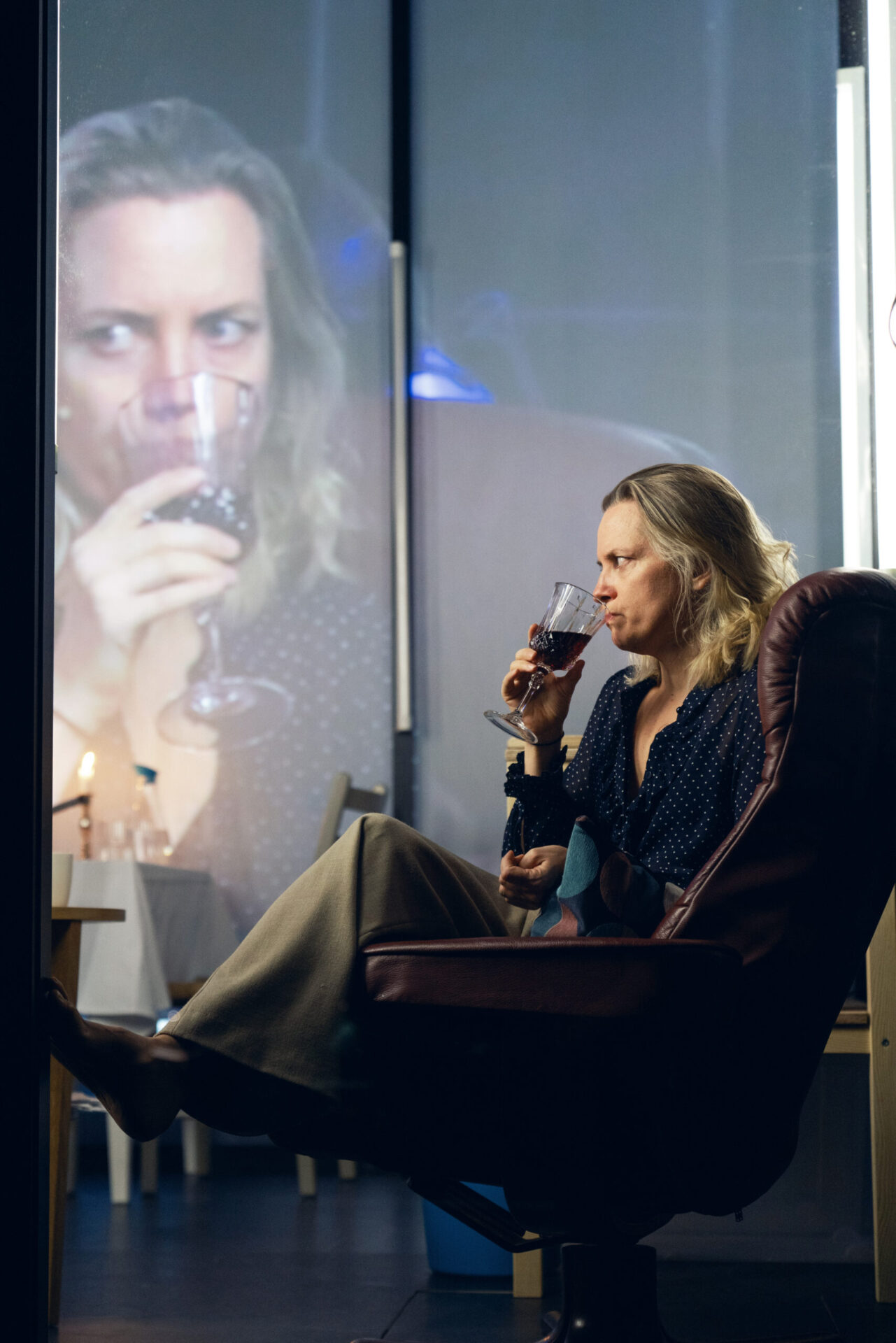 Kvinne sitter i en lenestol og drikker vin.