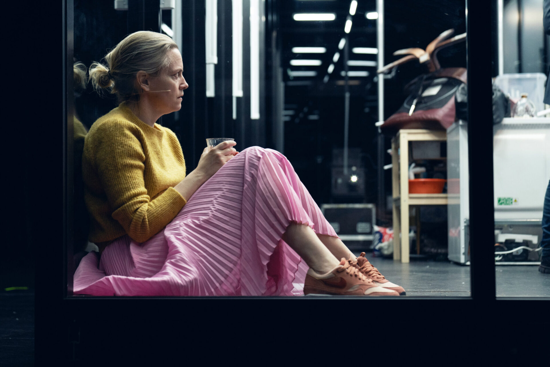 Kvinne i rosa skjørt sitter på gulvet.