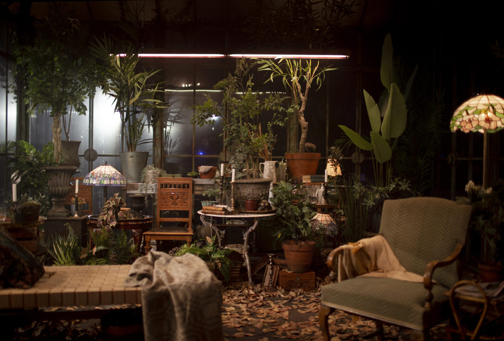 Interiøret i drivhuset med planter, lamper og stoler.