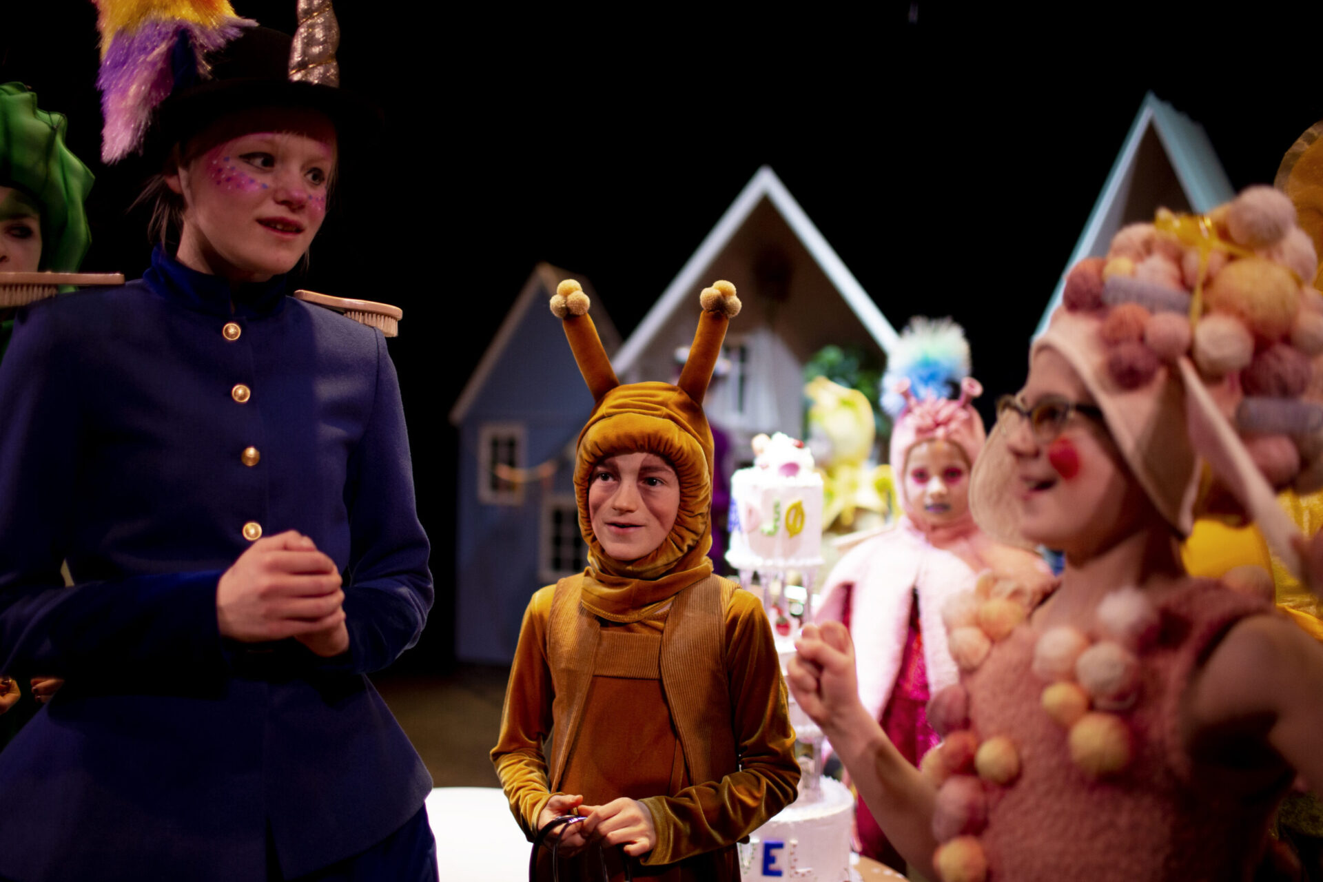 Unge skuespillere i fargerike kostymer snakker sammen.