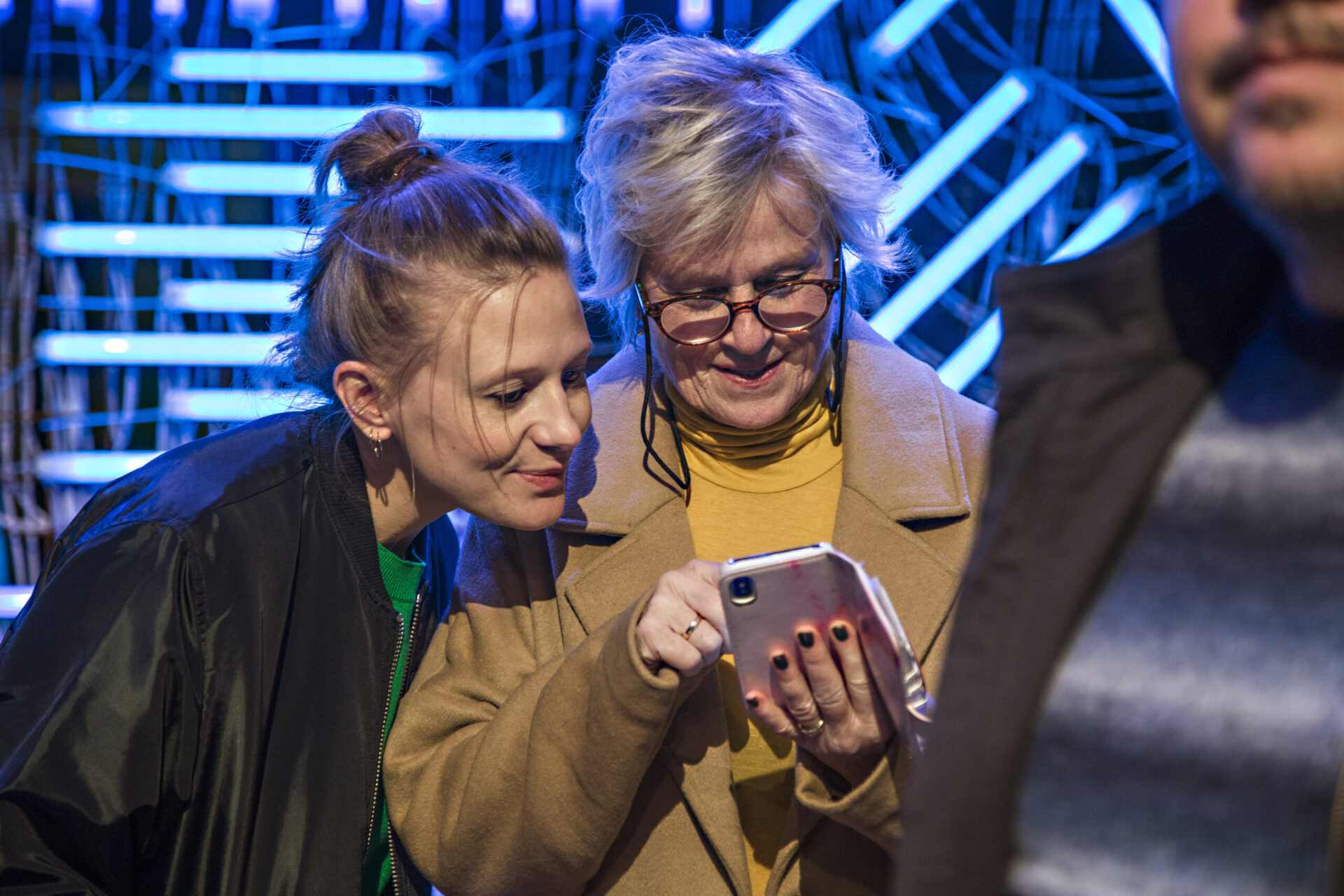 En eldre og en yngre kvinne ser på den eldre kvinnens mobil