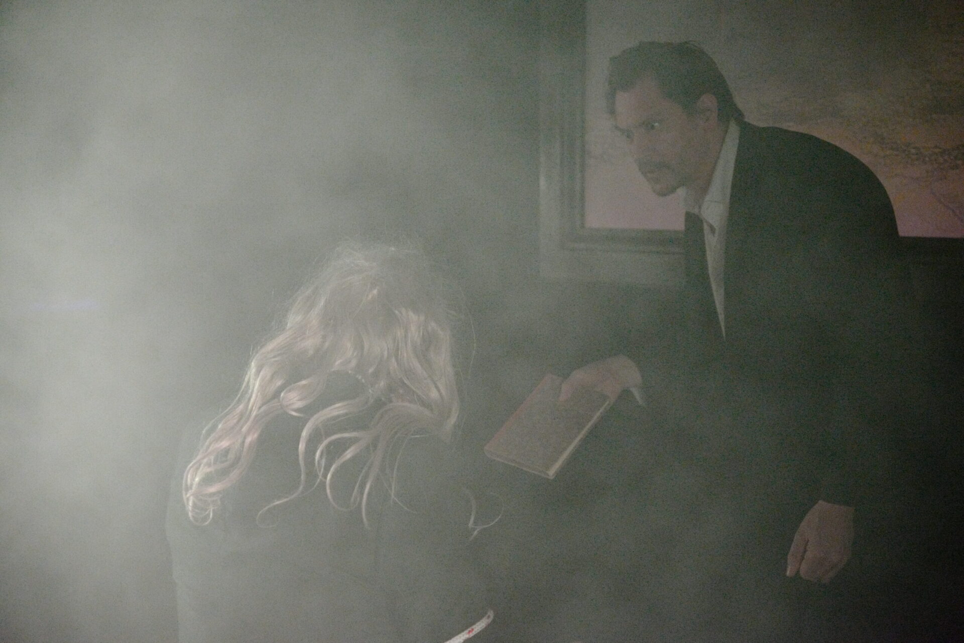 En mann og en dame ser på en bok. Mannen er sint og bildet er tåkete.