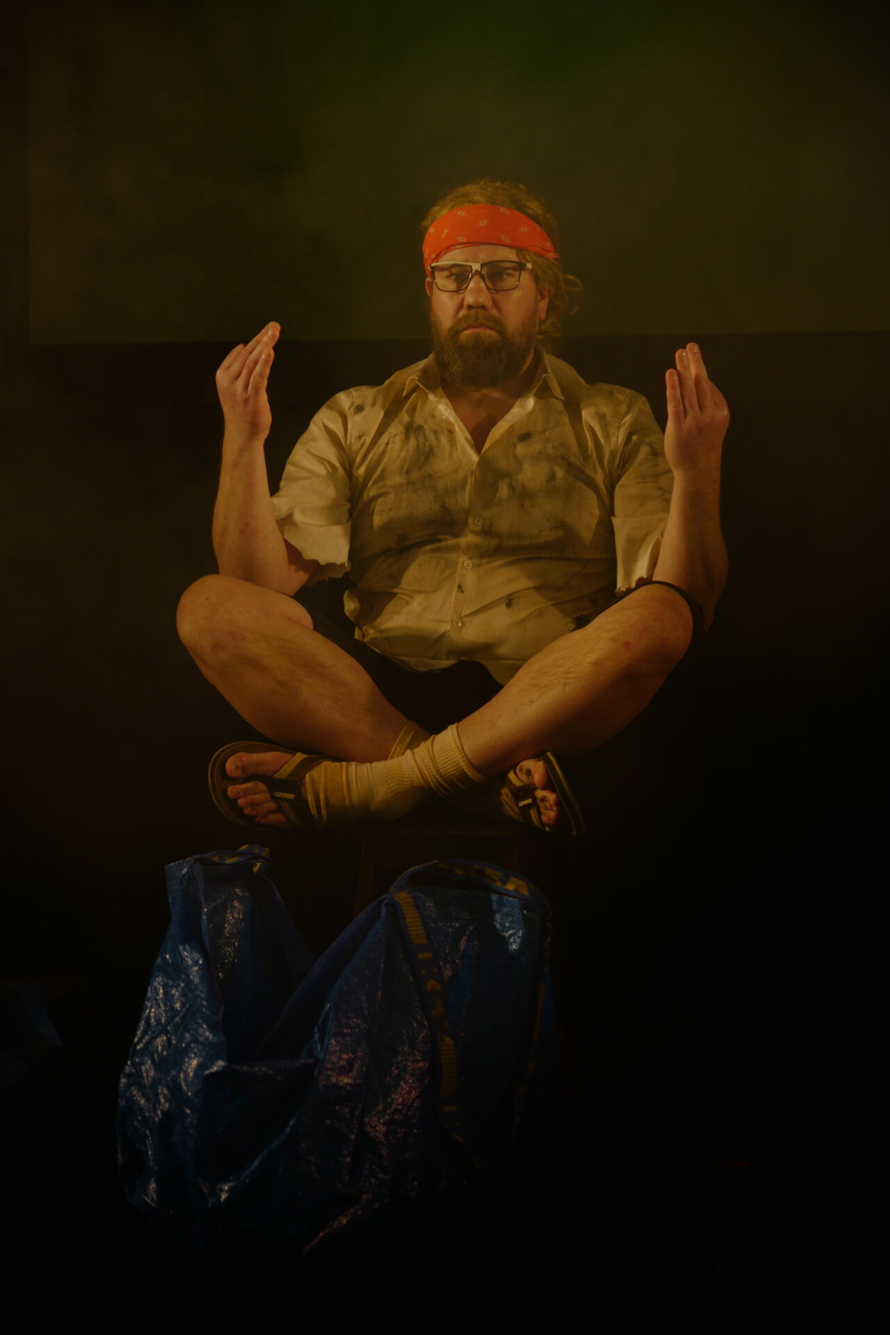 En mann med orange pannebånd i yogastilling.