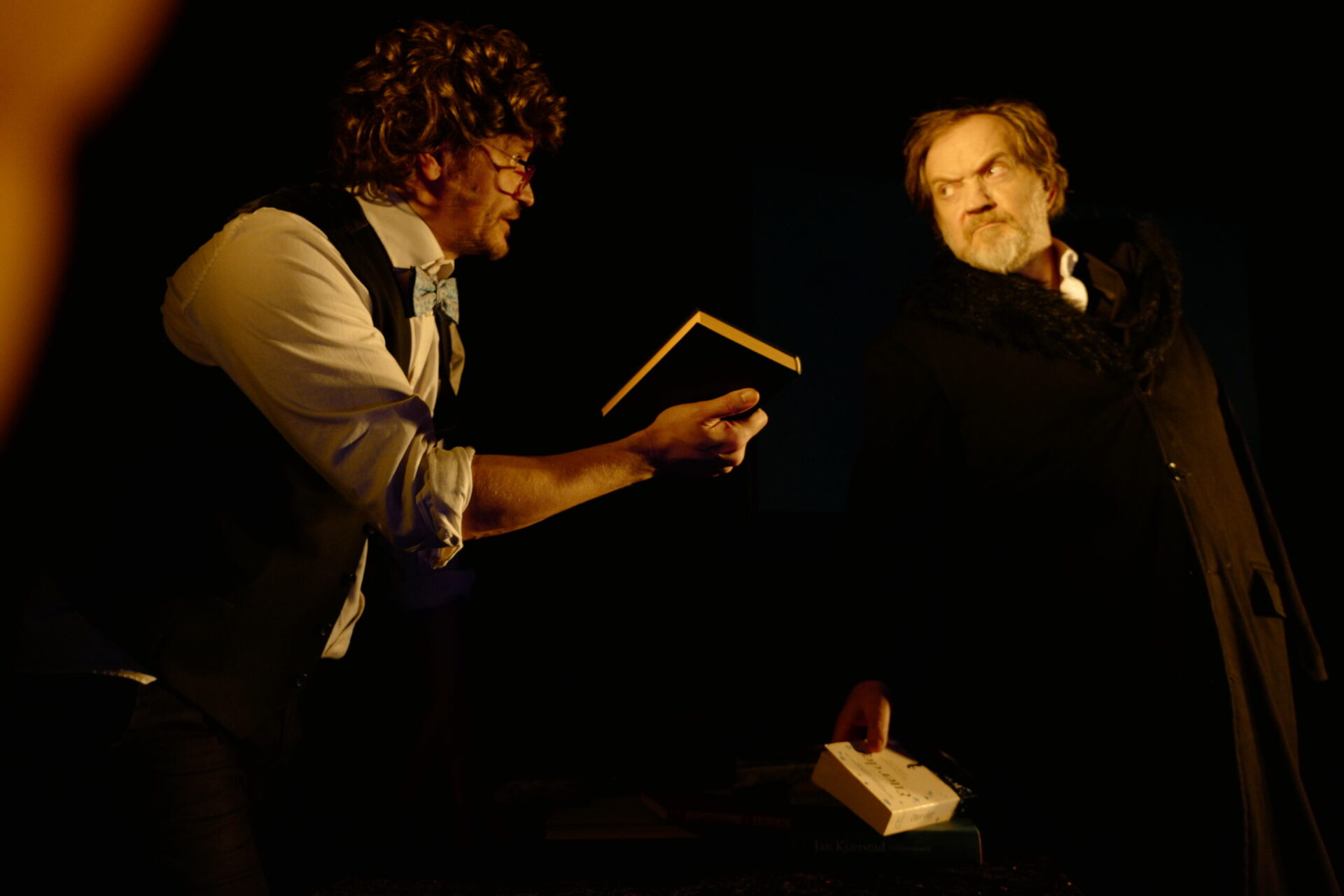 To menn snakker sammen og holder bøker i hendene.