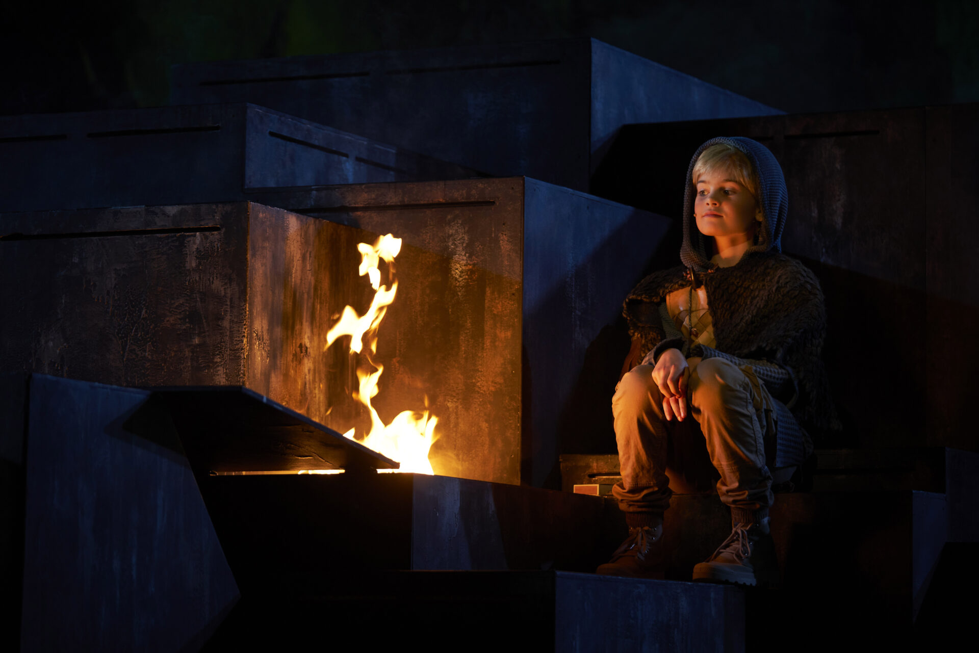 Liten gutt sitter foran et bål