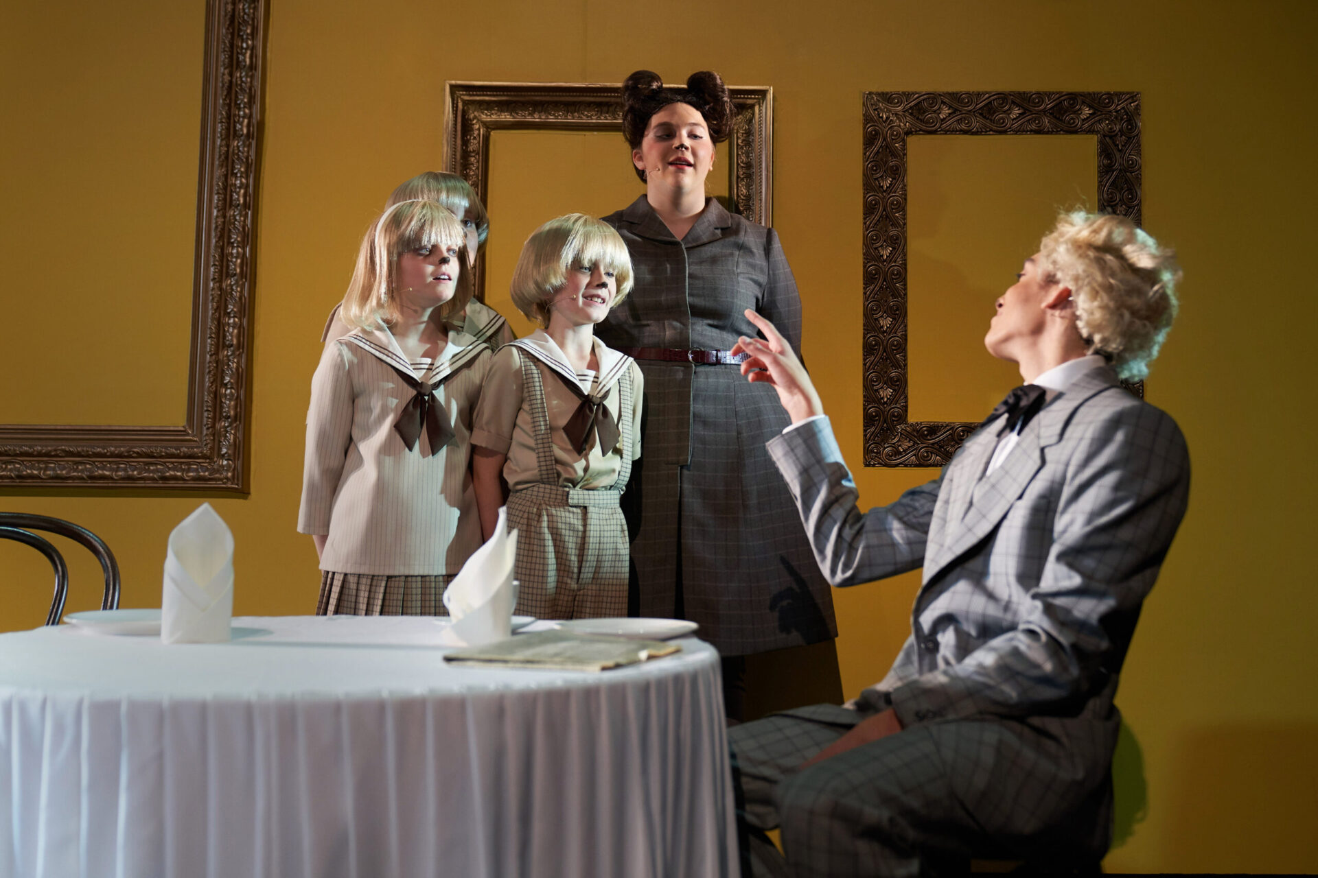 Tre valper og hundemor synger for en sittende hund ved et bord