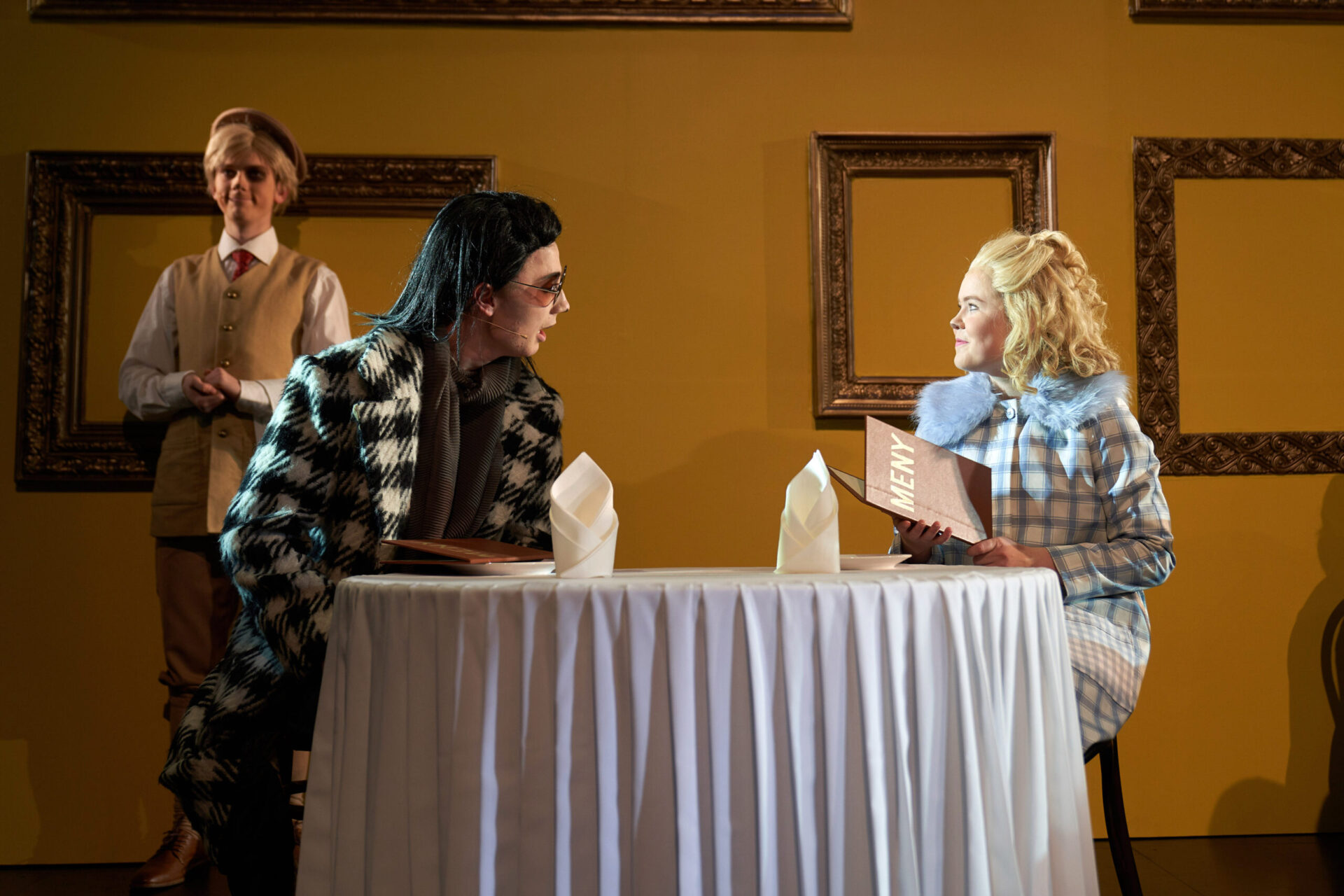 En katt og en hund sitter ved et restaurantbord