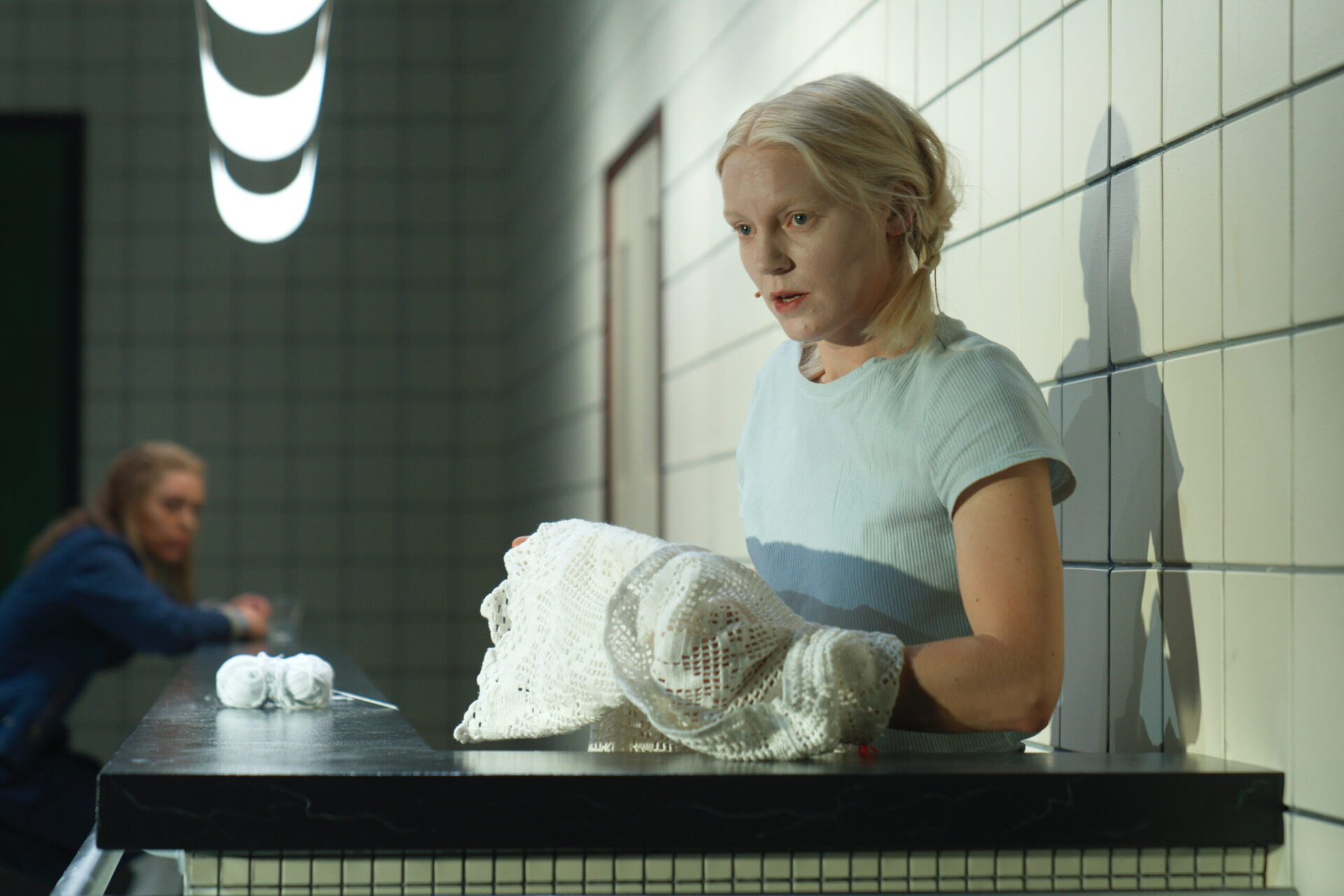 En kvinne står med et hekleteppe