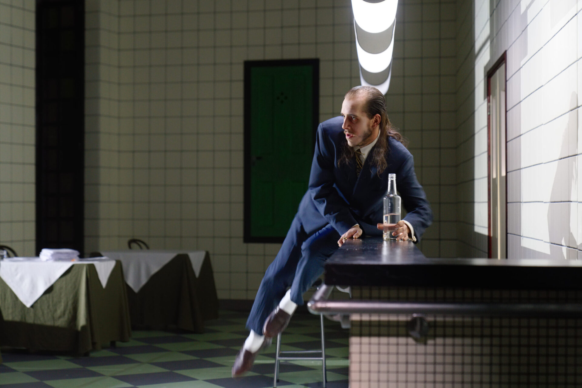 En mann ligger på en bardisk og har en flaske i hånden