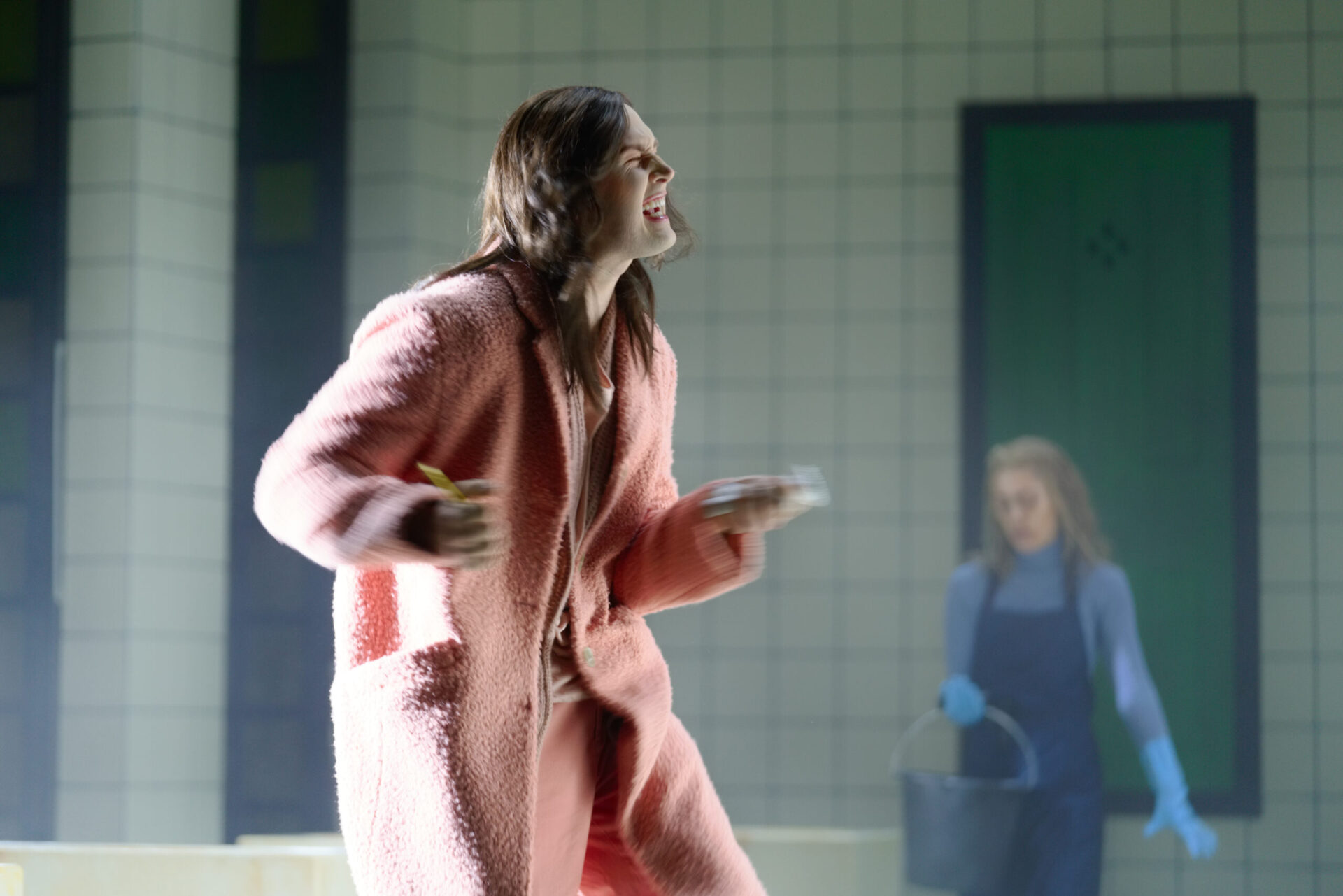 En mann i rosa tøy står og skriker på scenen