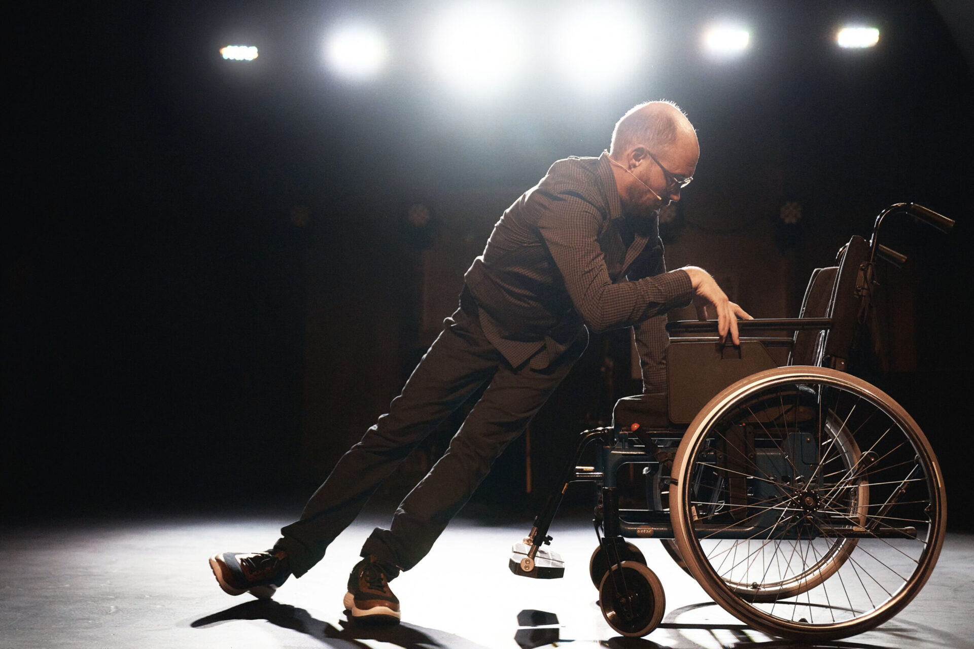 En mann har falt ut av rullestolen og prøver å komme seg opp i stolen ved egen hjelp