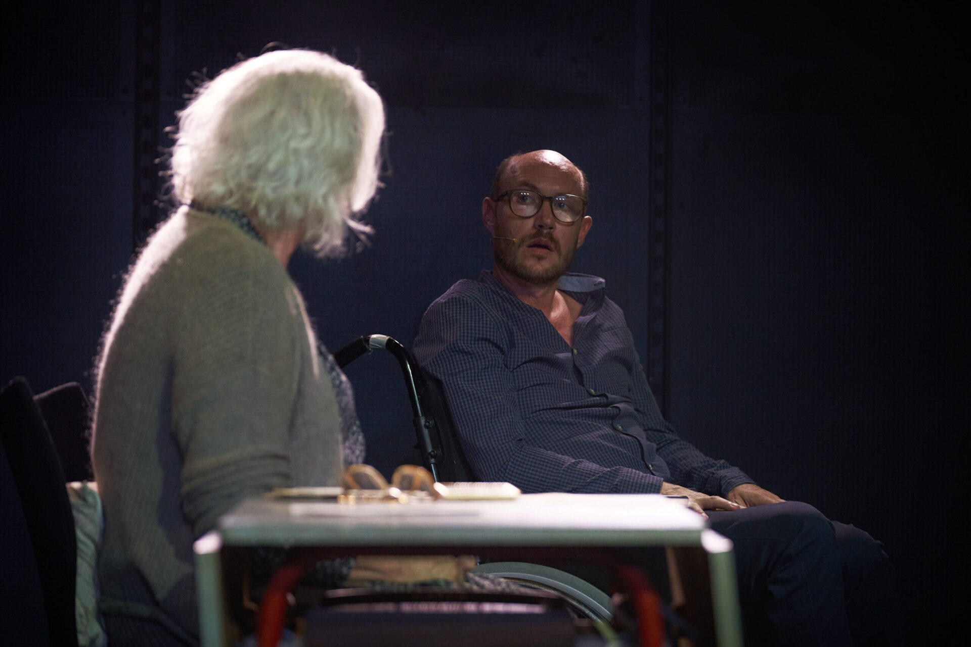 Mann i rullestol snakker med en eldre kvinne