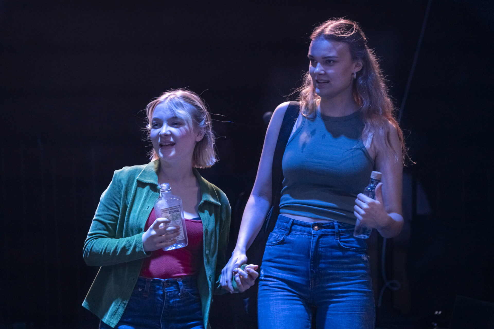 To jenter med spritflasker ser ut i rommet.