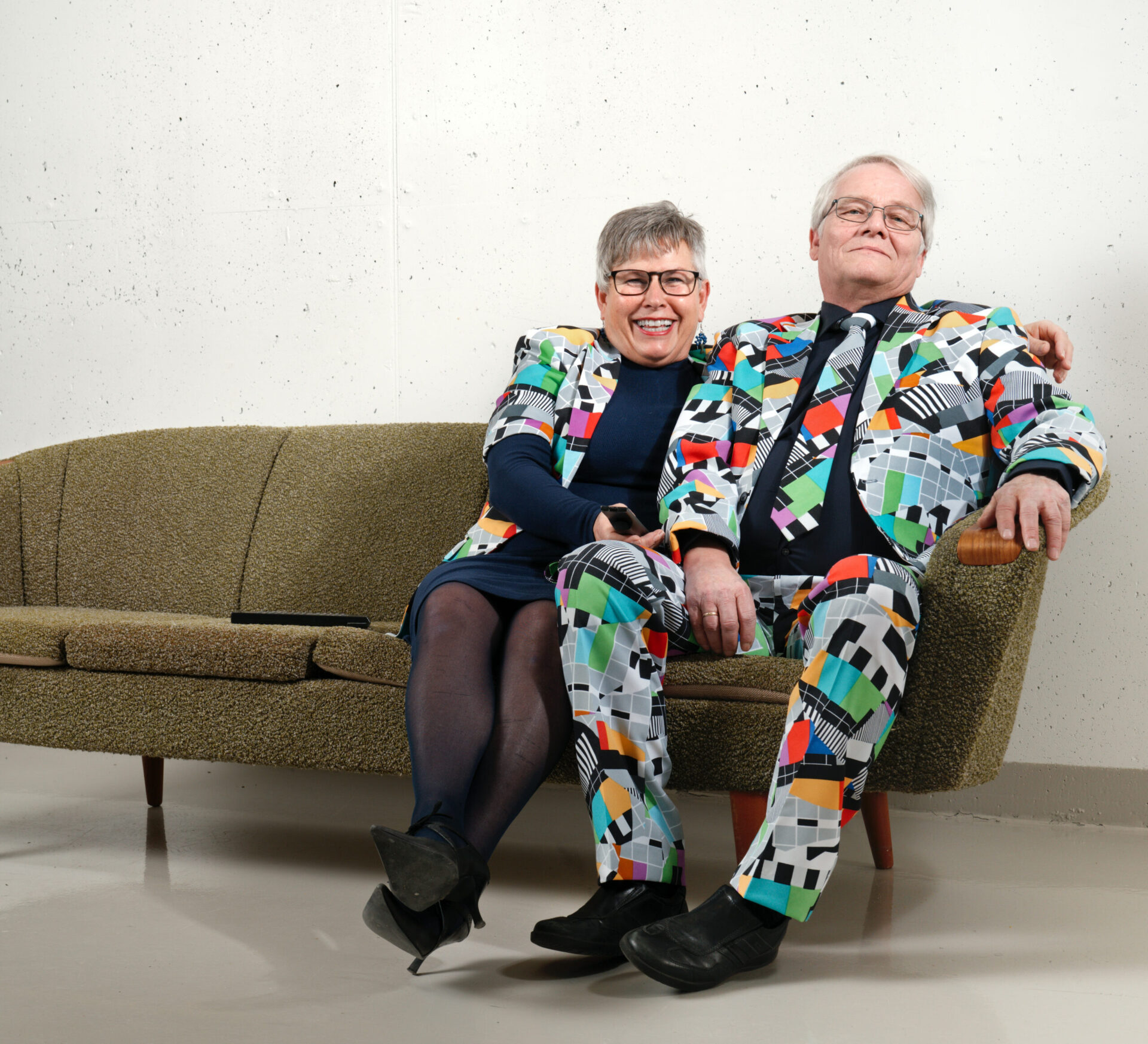 En mann og en kvinne som sitter i en sofa i klær som har mye forskjellig mønster og farger