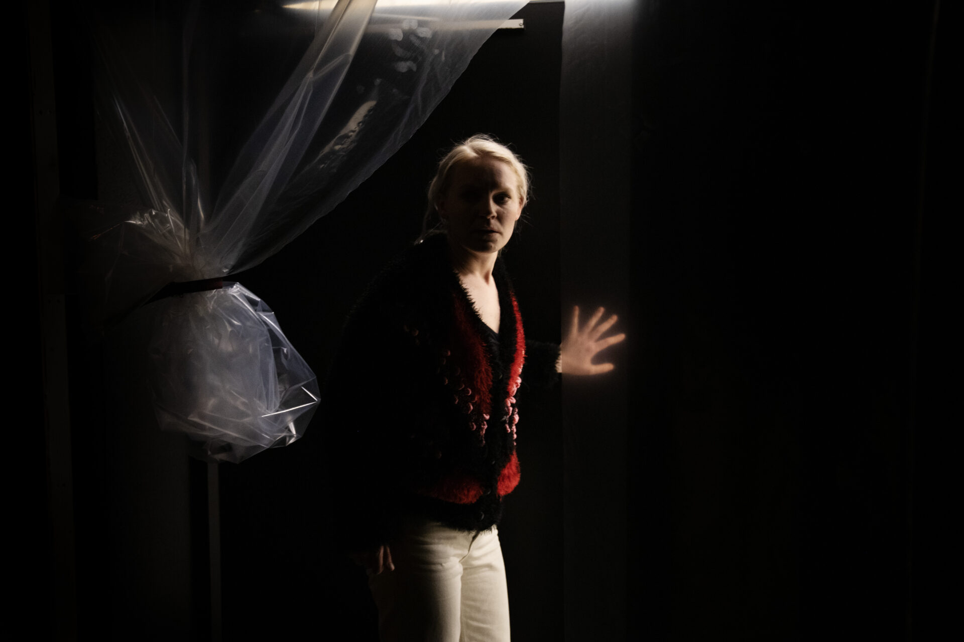 En kvinne i rød jakke ser inn i kamera mens hun ser redd ut.