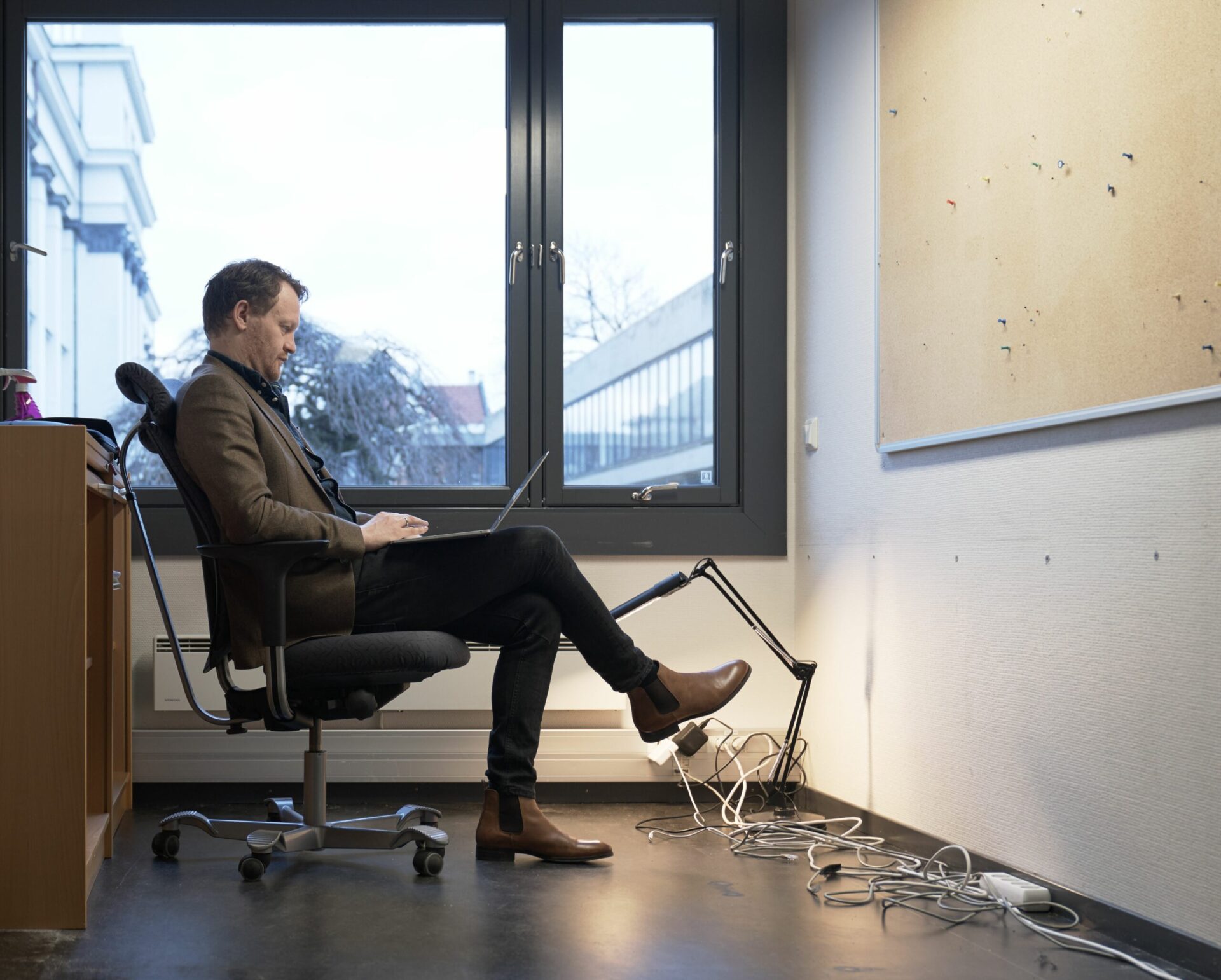 Glenn André Kaada sitter i en stol på et tomt kontor