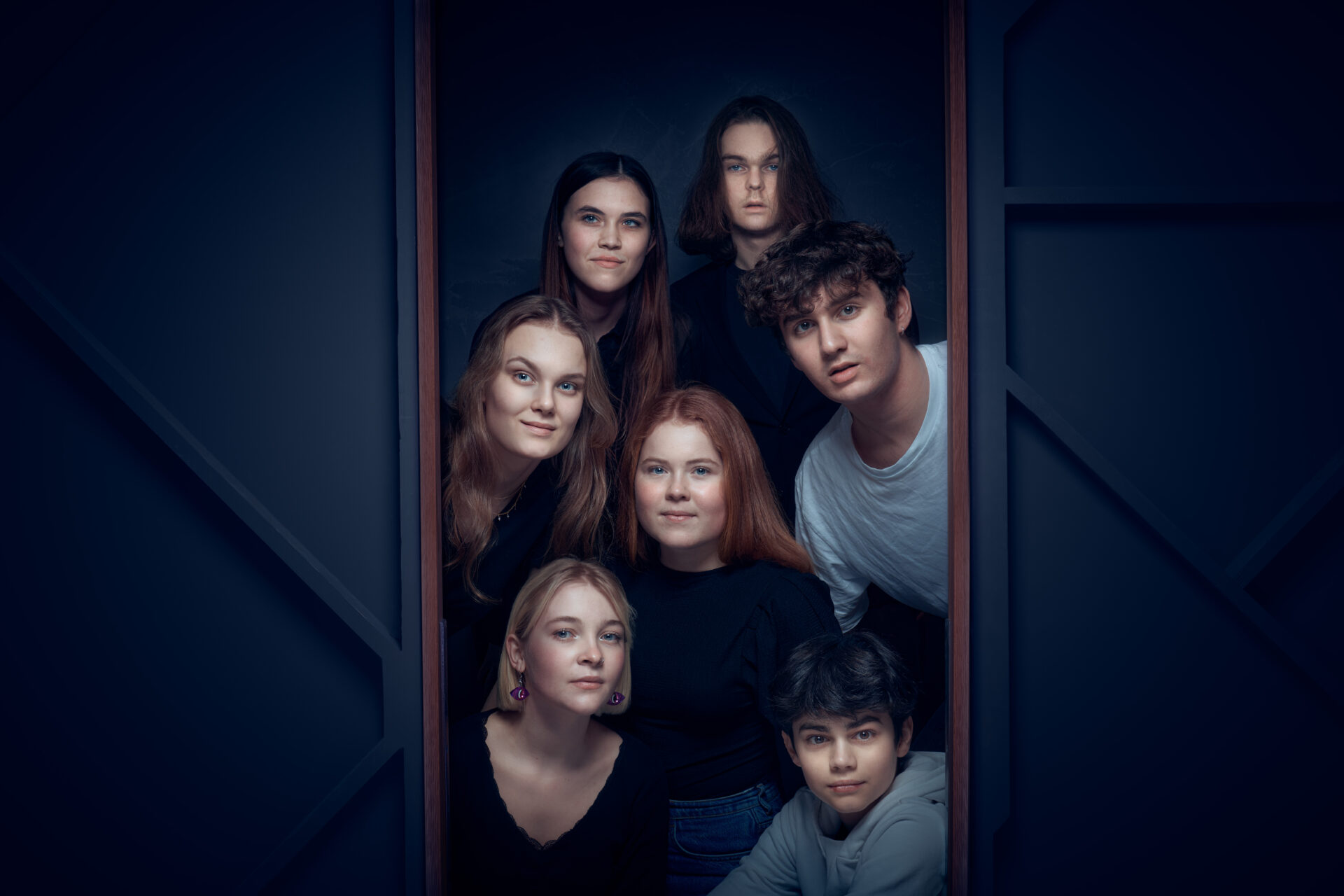 Syv unge mennesker i en dør.