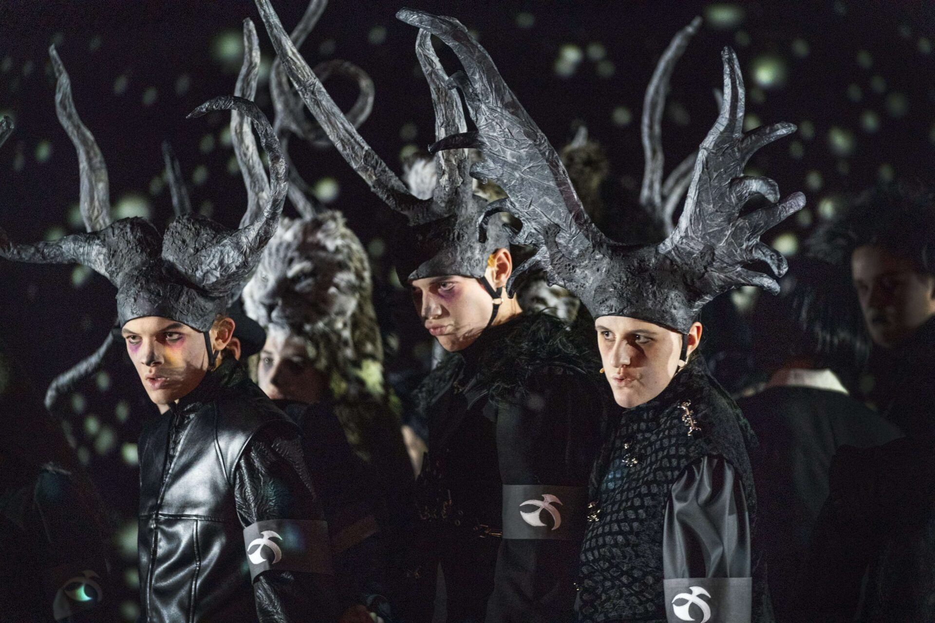 Unge skuespillere i mørke kostymer med store horn.