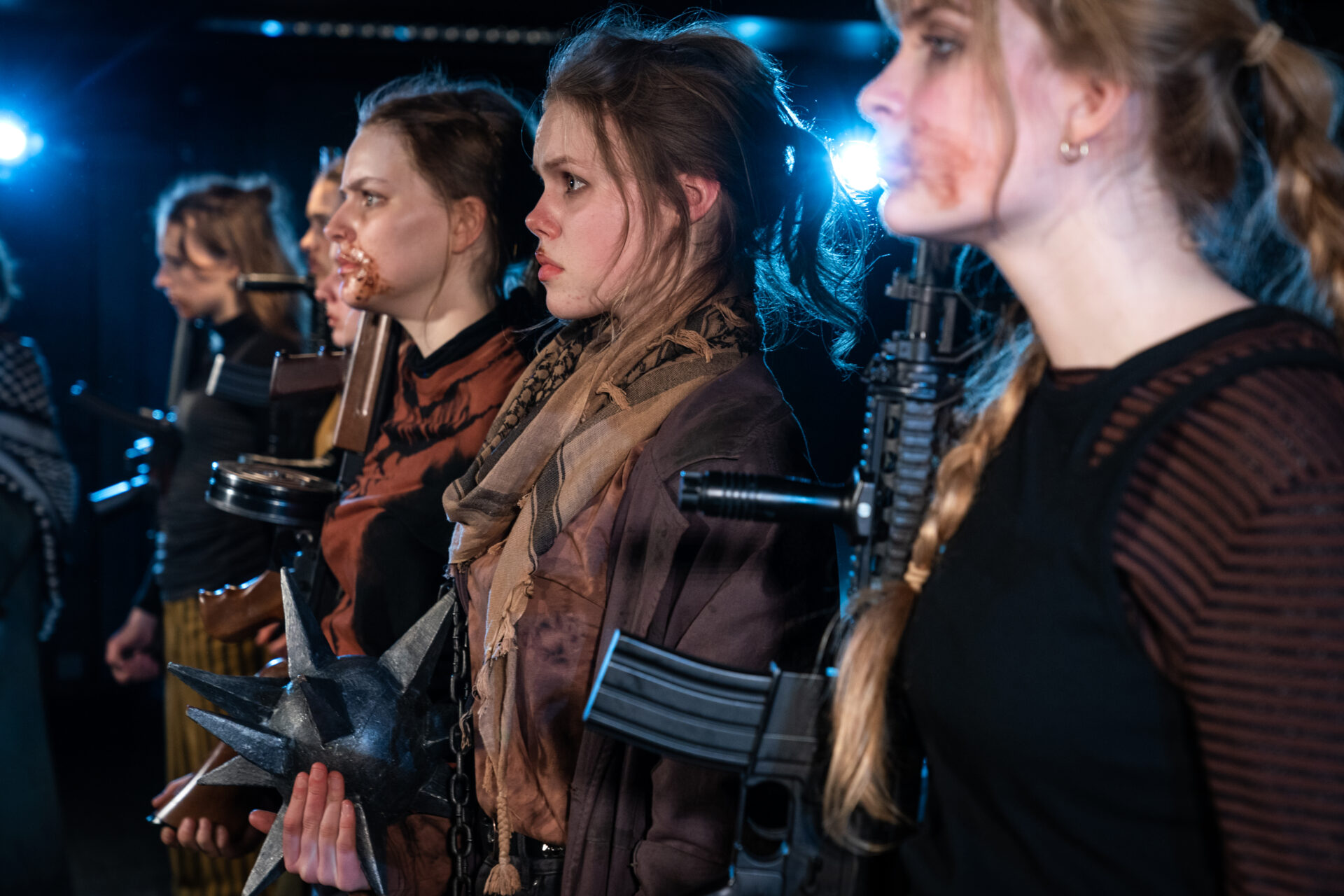 Tre jenter med maskingevær som står i giv akt.