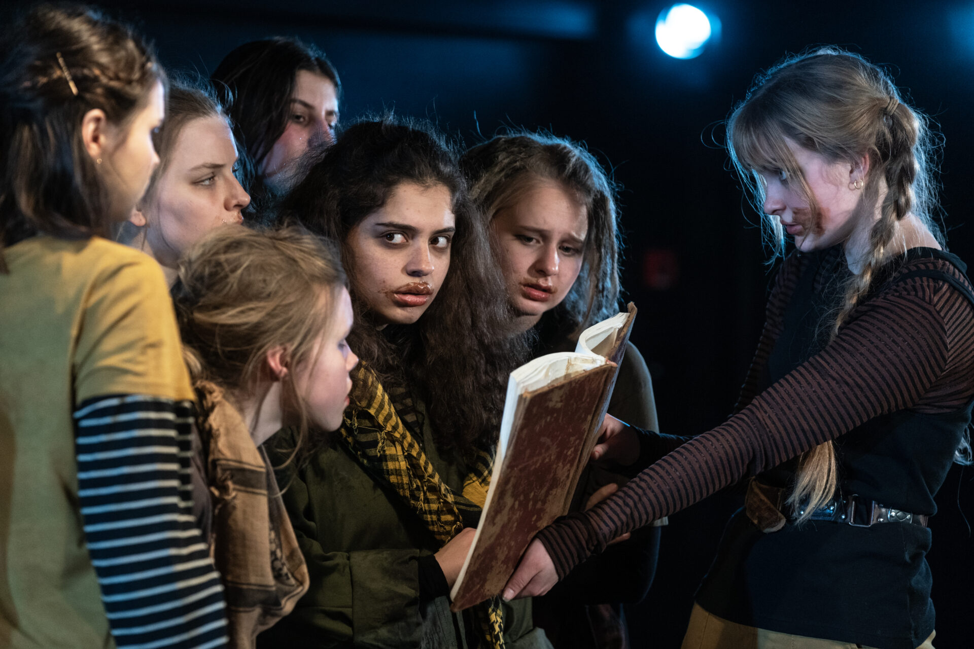 En jente som viser 7 andre jenter hva som står skrevet i en bok.