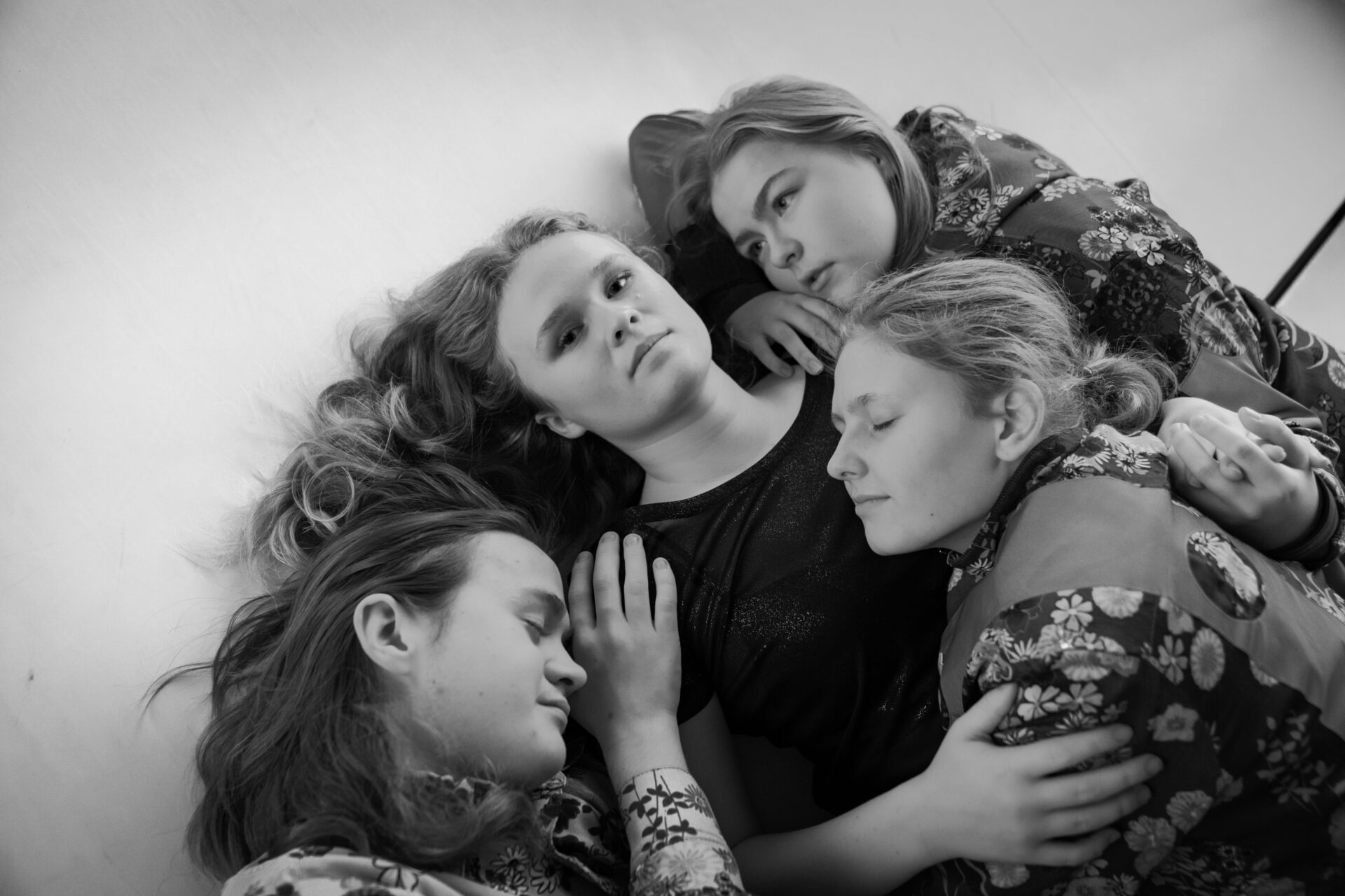 En gutt og tre jenter som ligger på gulvet og omfavner hverandre.