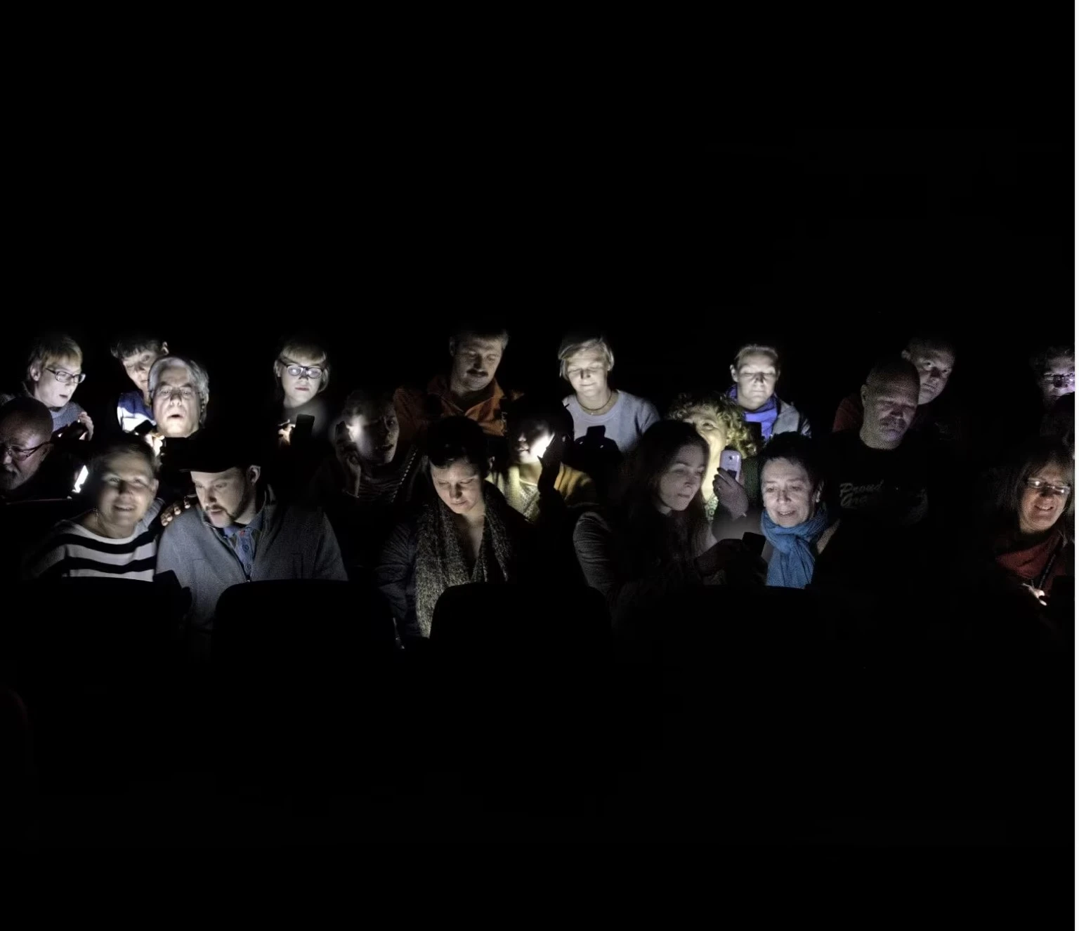 Publikum som ser på mobiltelefon i teatret