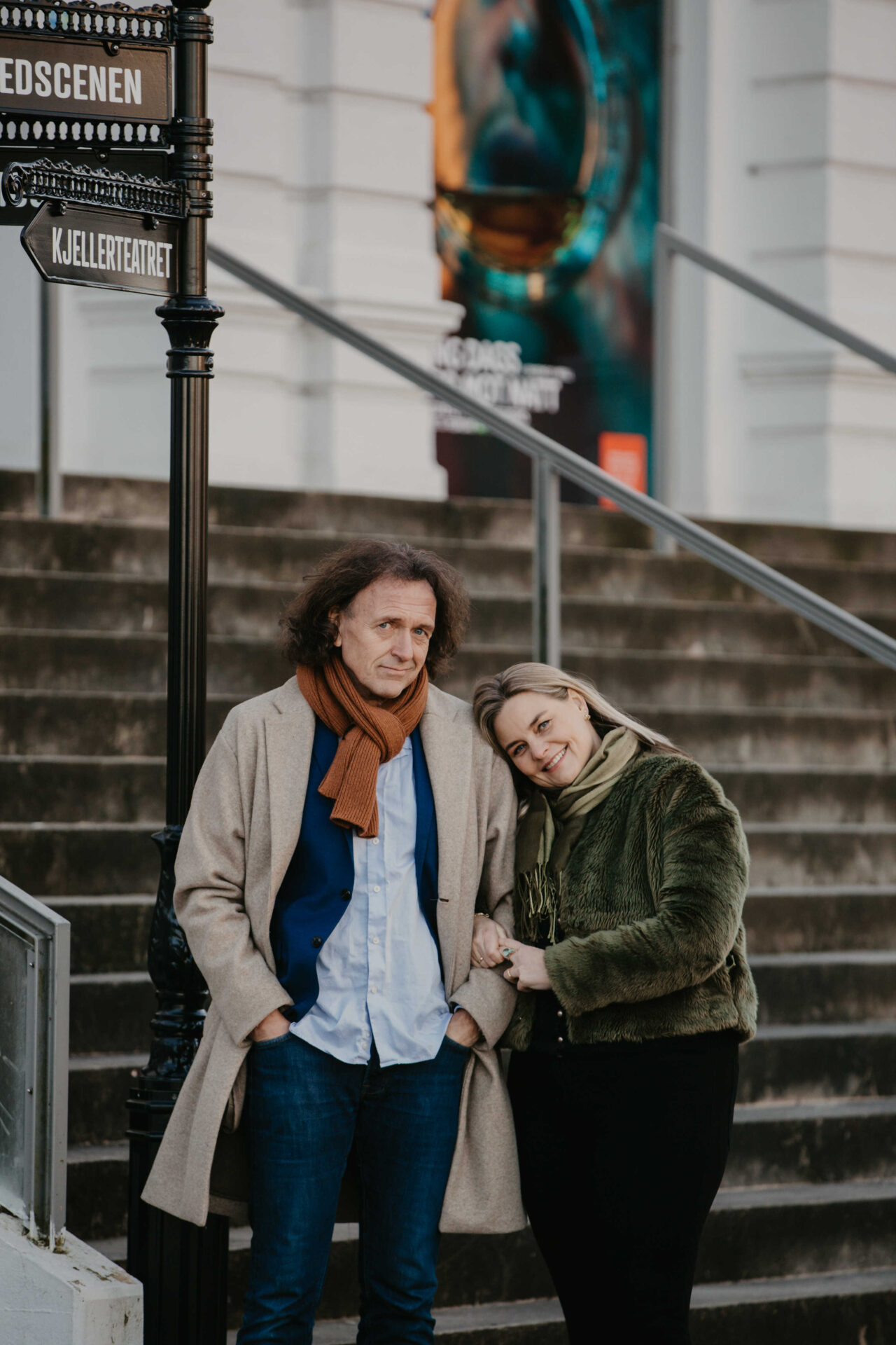 Et par som står ved veiskiltet til de ulike scenen på teatret