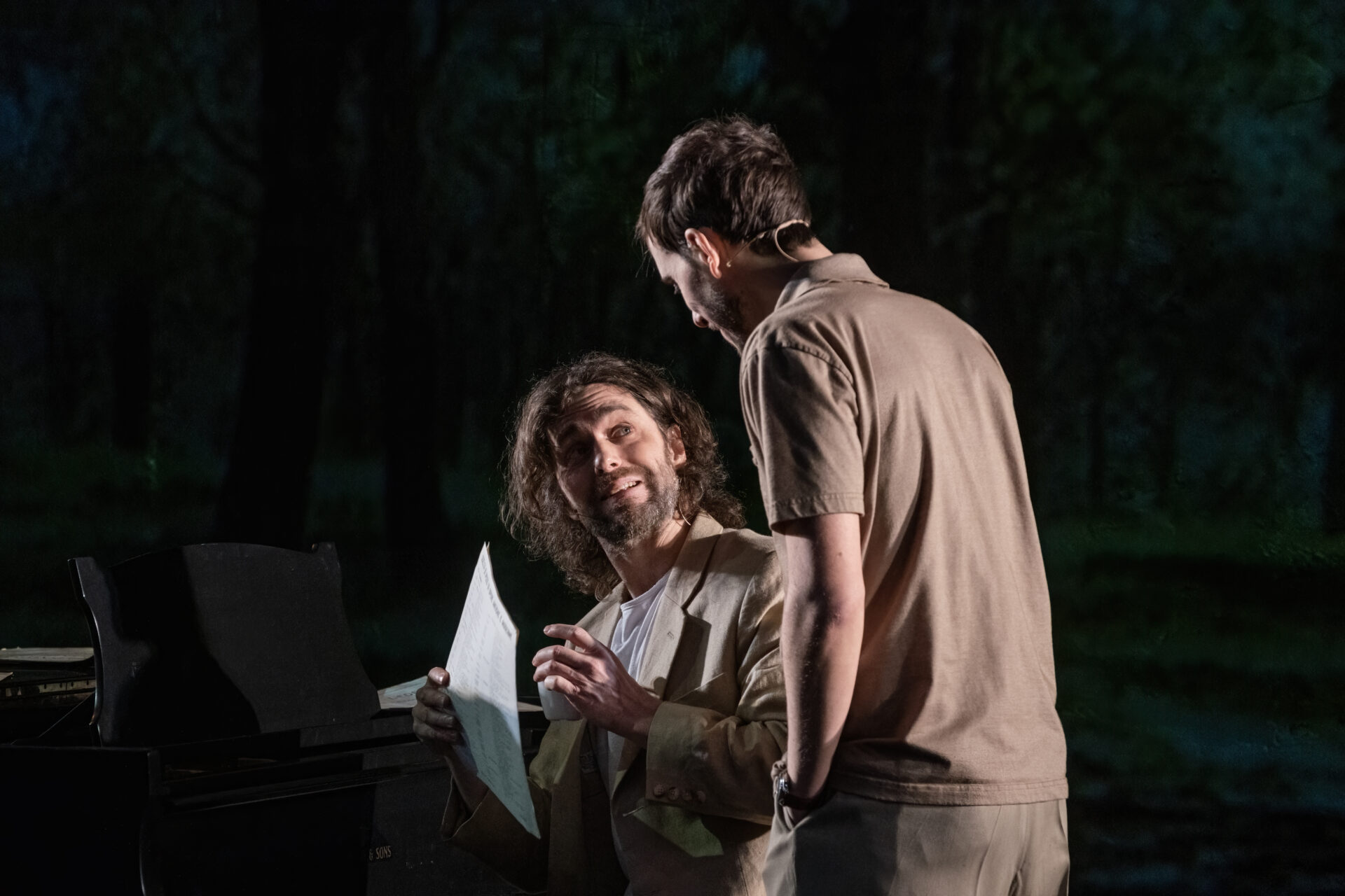 To brødre. En som sitter ved et piano og viser noter til sin bror.