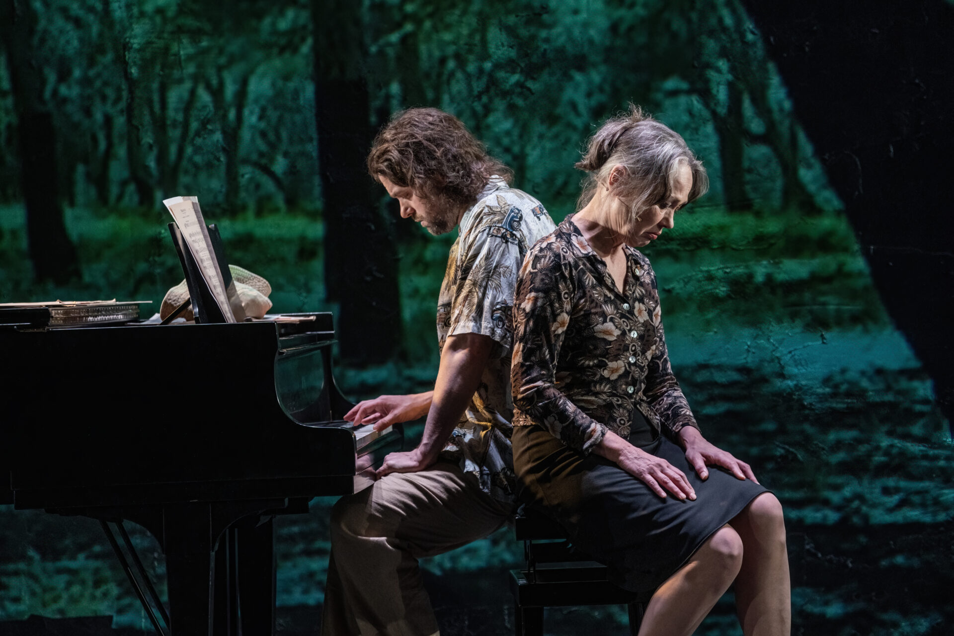 Mor og sønn som sitter med ryggen til hverandre ved et piano