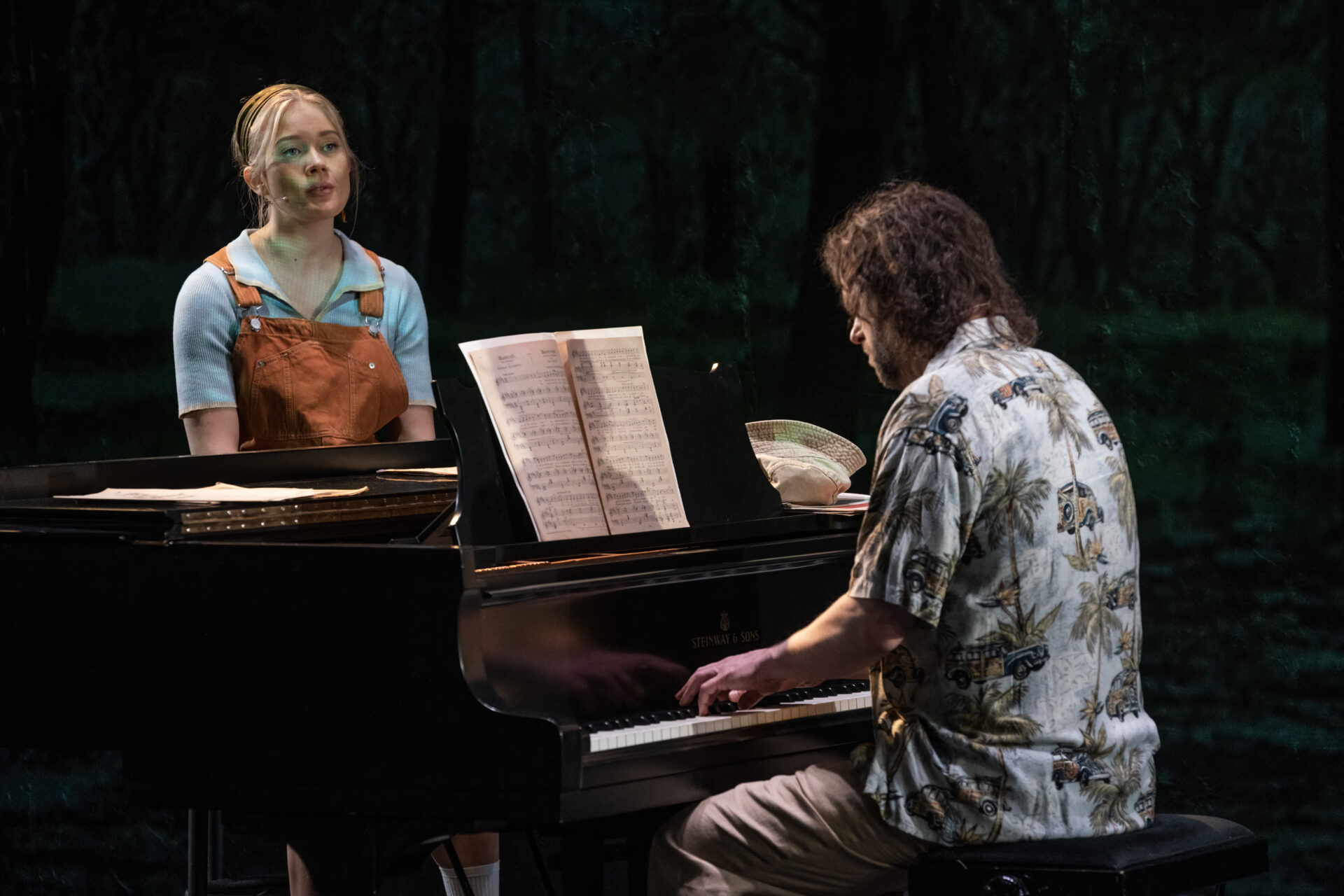 Mann som spiller piano og en kvinne som sitter ved et pianoet og lytter