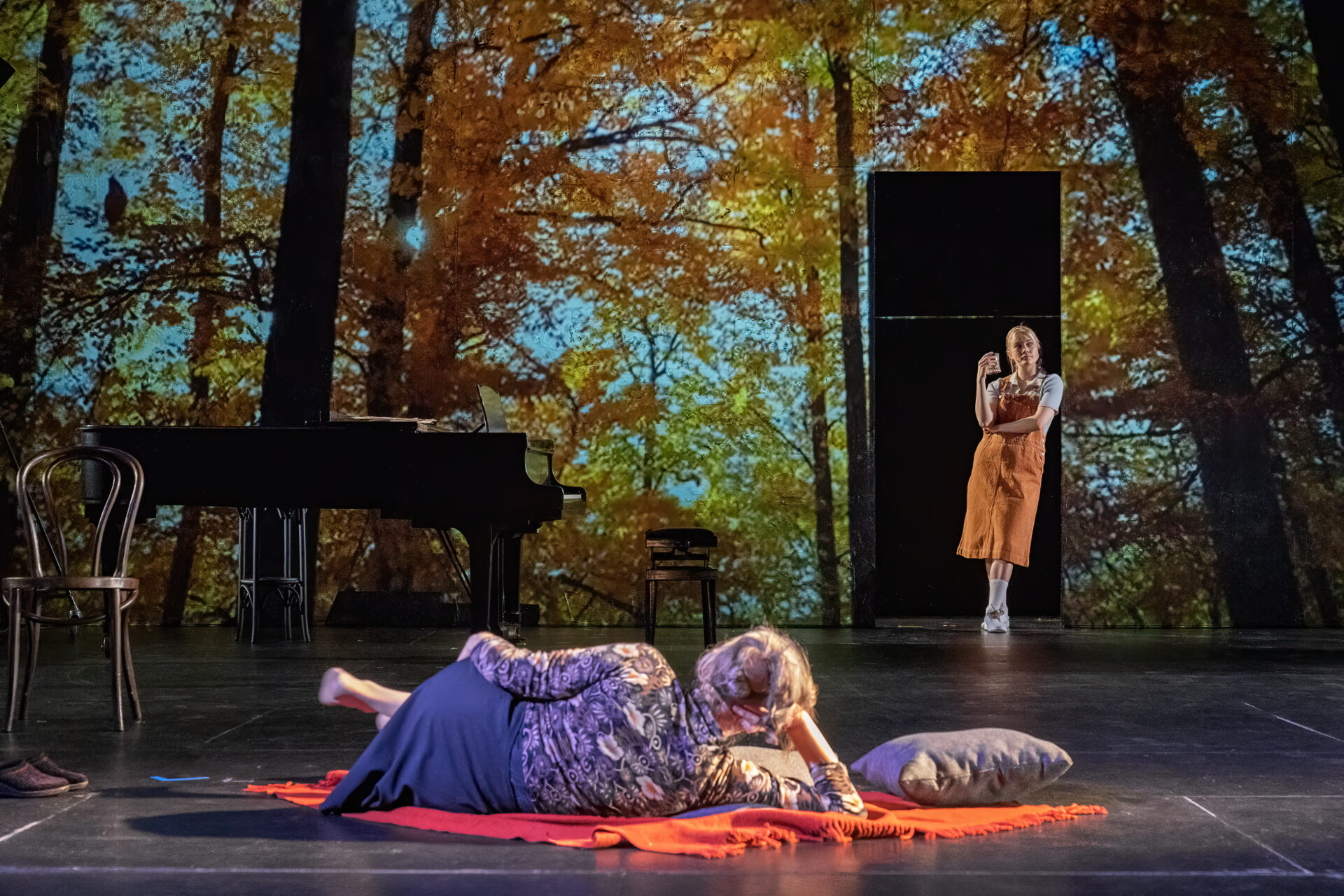 En eldre kvinne som ligger på gulvet og ser på en yngre kvinne i en døråpning