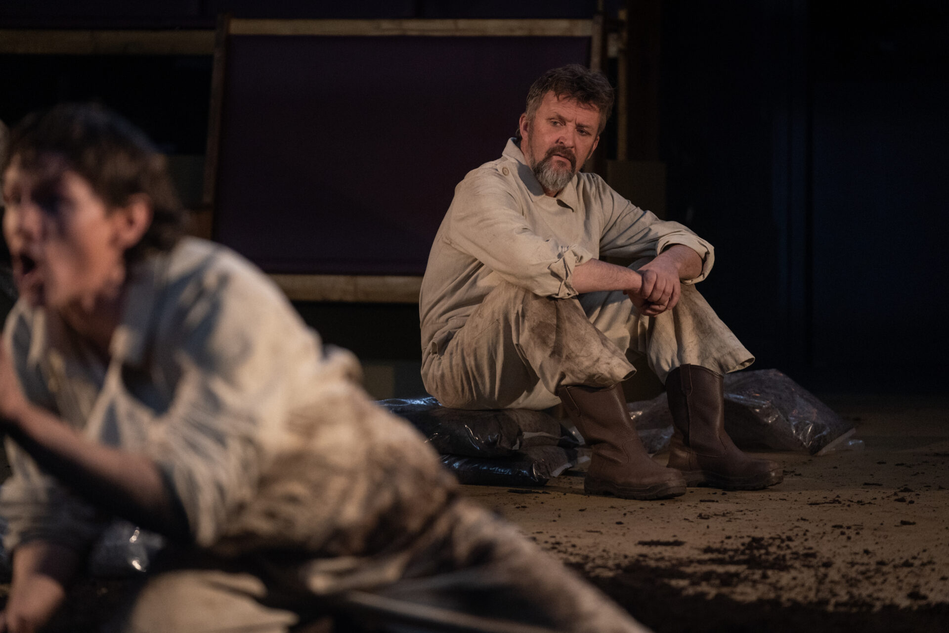 En mann sitter på moldsekker og ser på en annen mann som snakker