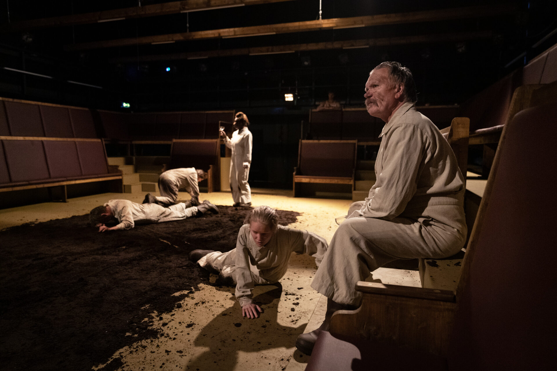 Menn og kvinner som ligger i gjørma og en mann som sitter på en benk