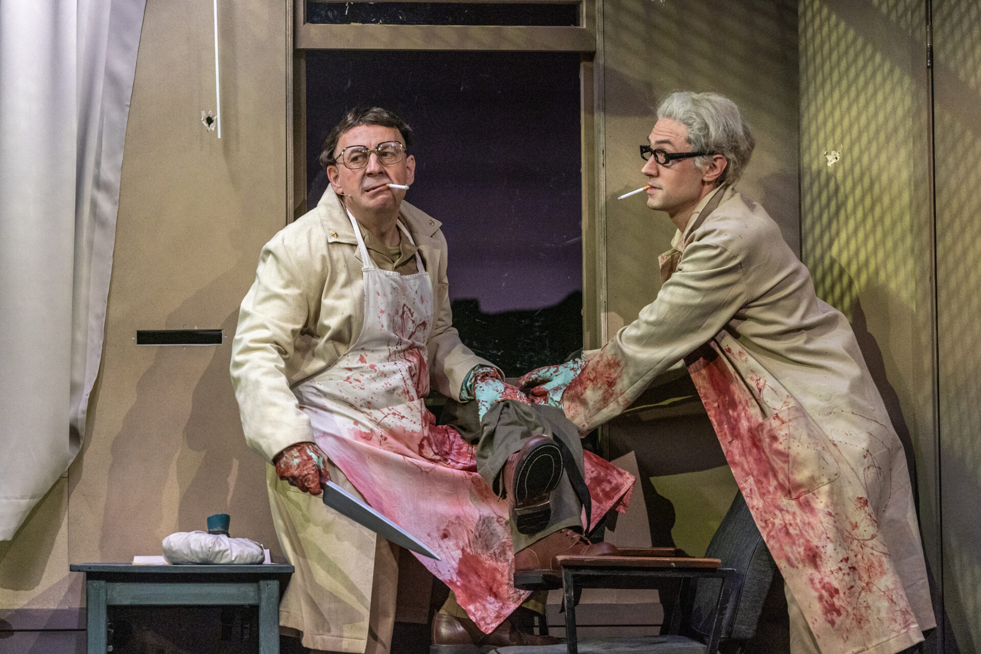 To leger innsmurt i blod som er i ferd med å foreta en amputasjon