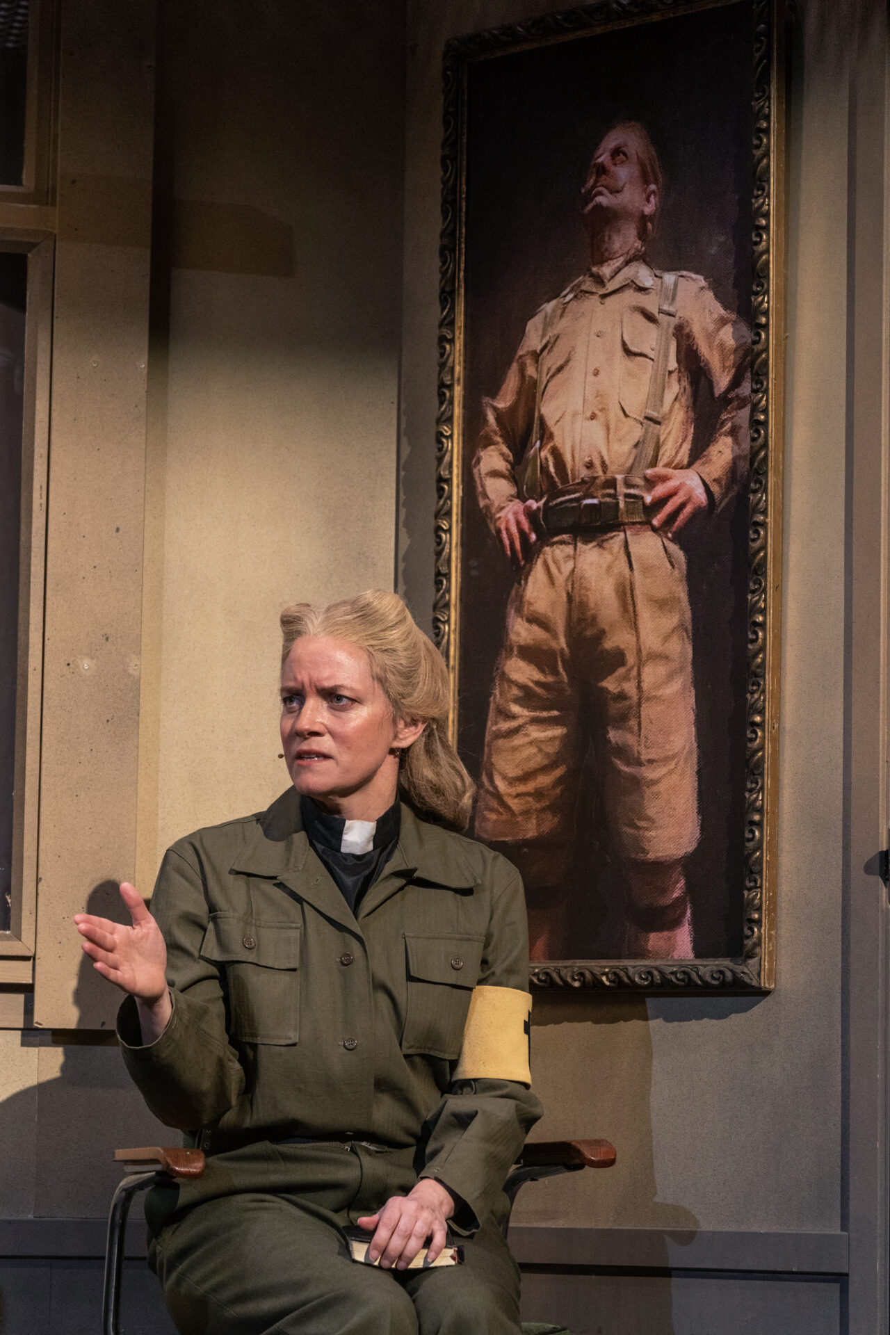 En feltprest som sitter under et maleri av en oberst