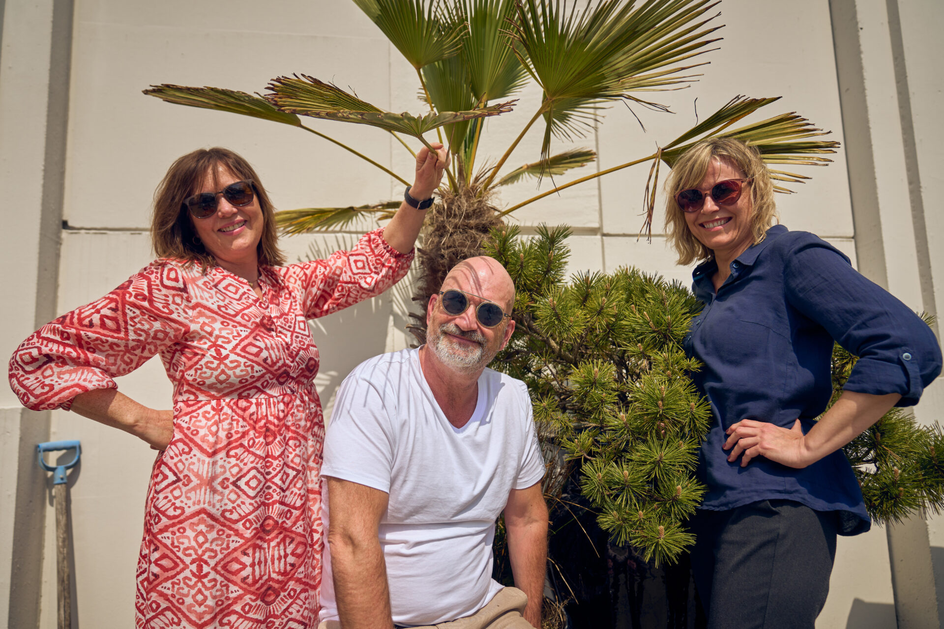 Tre mennesker med solbriller, smiler til kamera