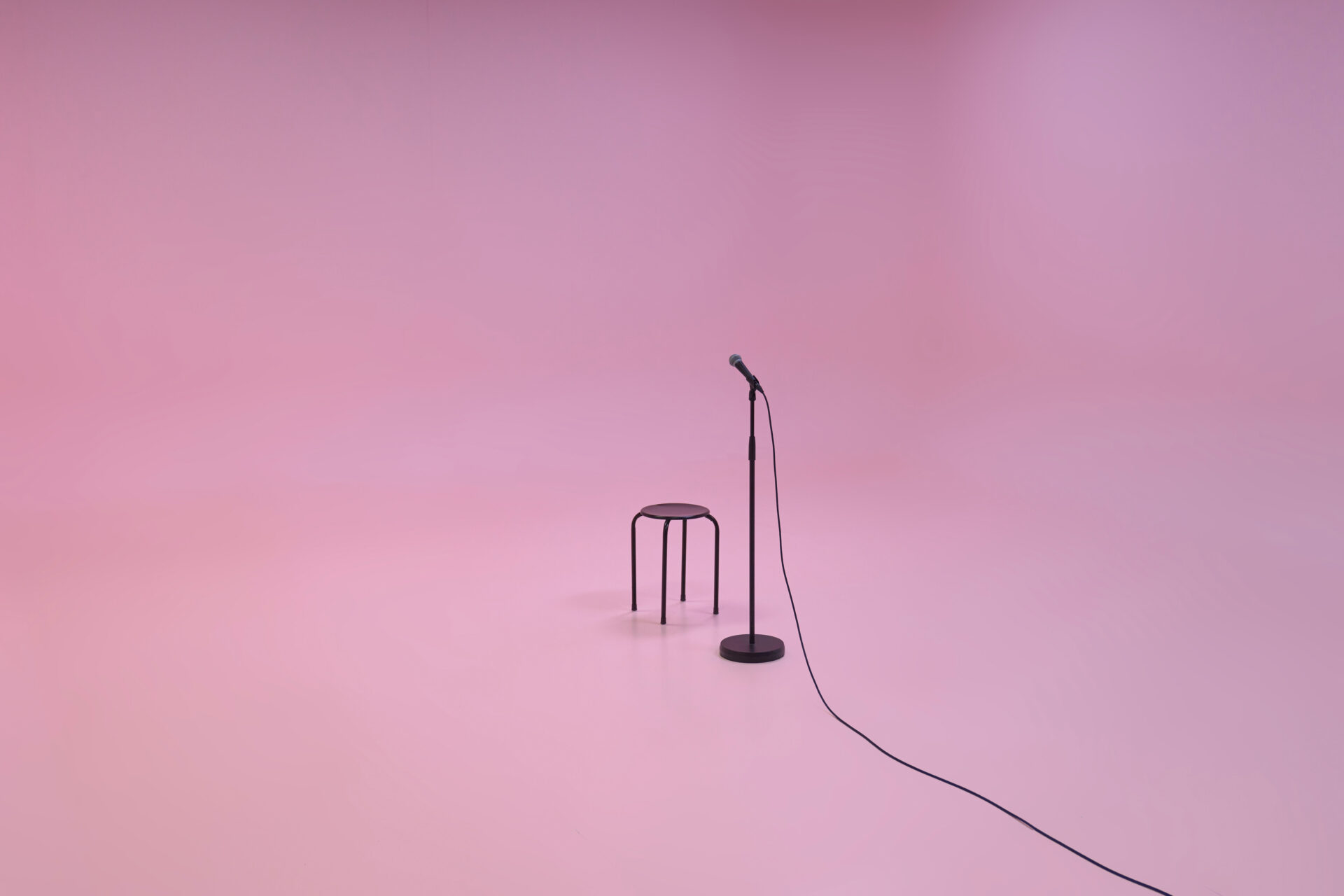 En mikrofonstativ og en krakk i et rosa rom