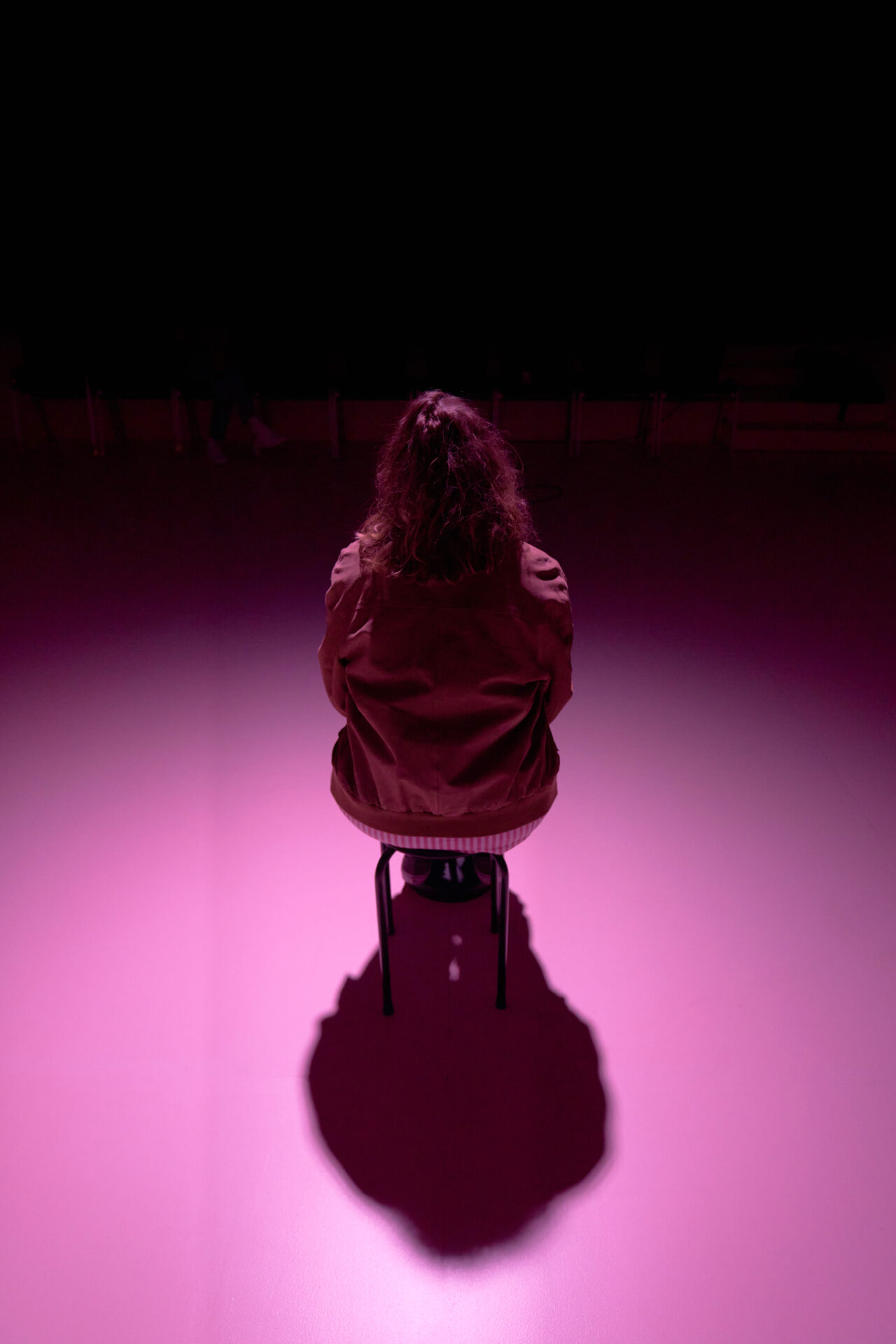 Kvinne som sitter på en krakk i et rosa rom