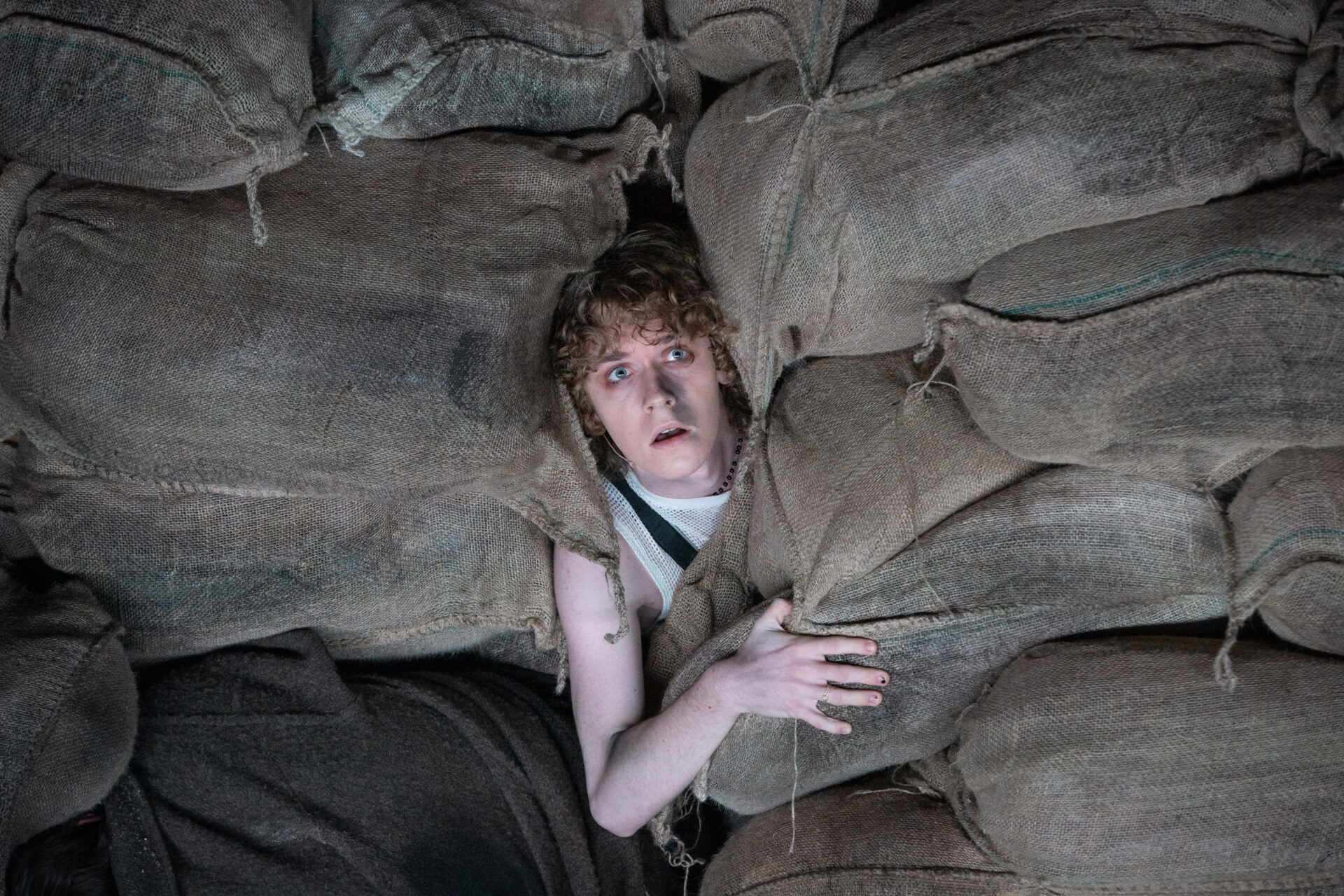 En ung mann ligger gjemt blant strie sekker