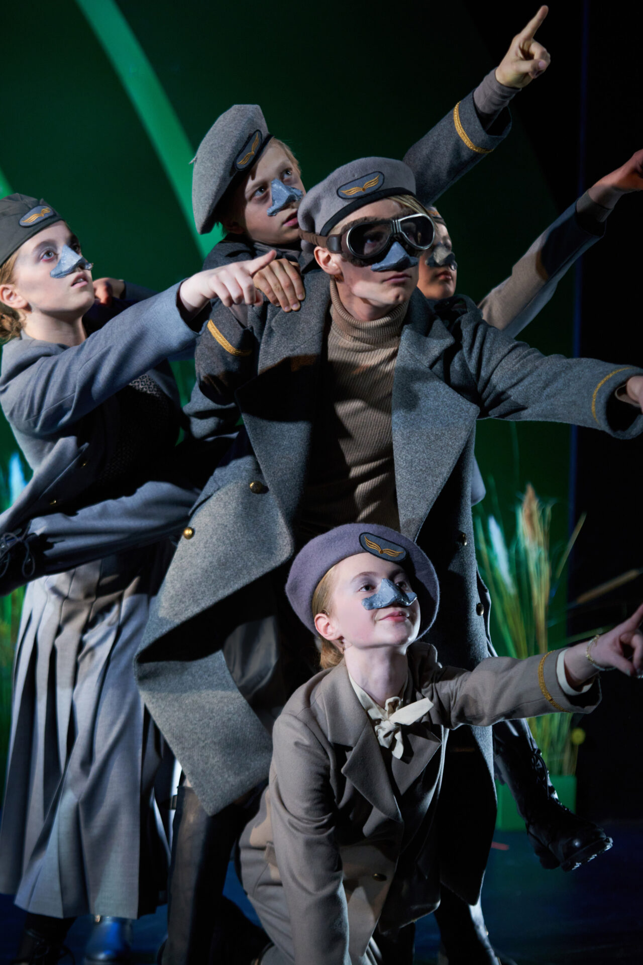 4 barn i uniform peker mot høyre