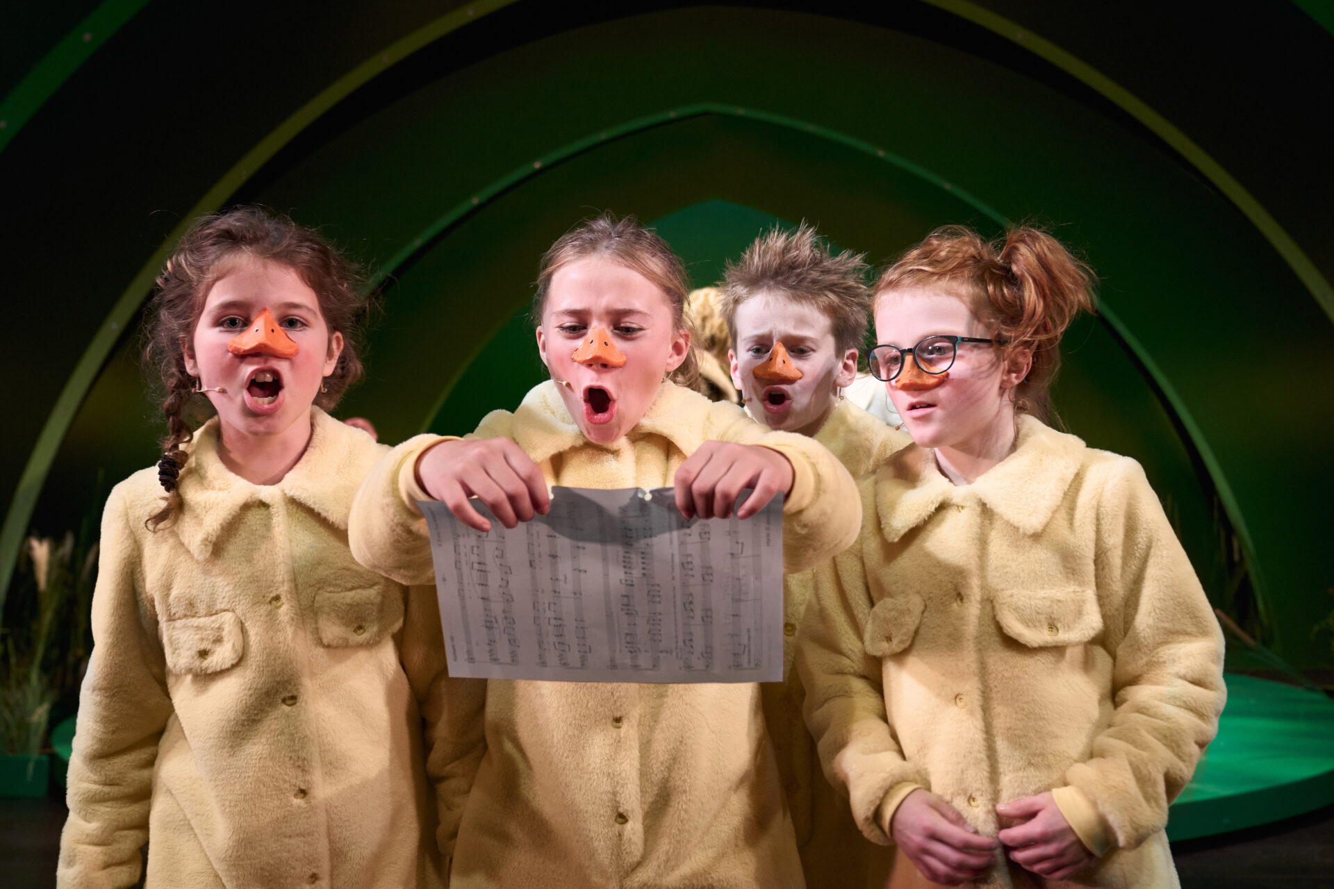 4 barn med nebb ser på ark med noter å synger