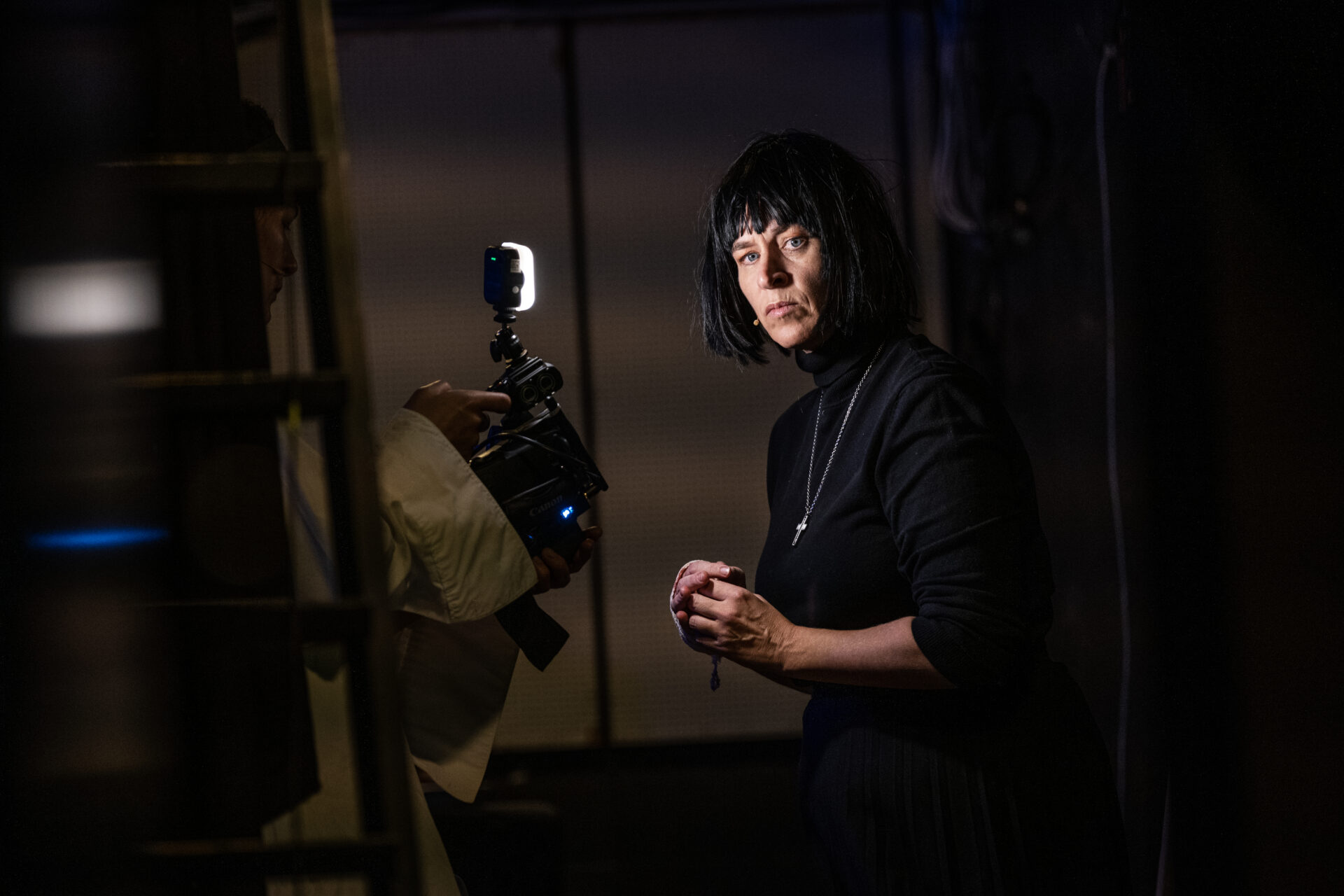 En kvinne med et halssmykke med kors, som titter med seriøst blikk på kamera